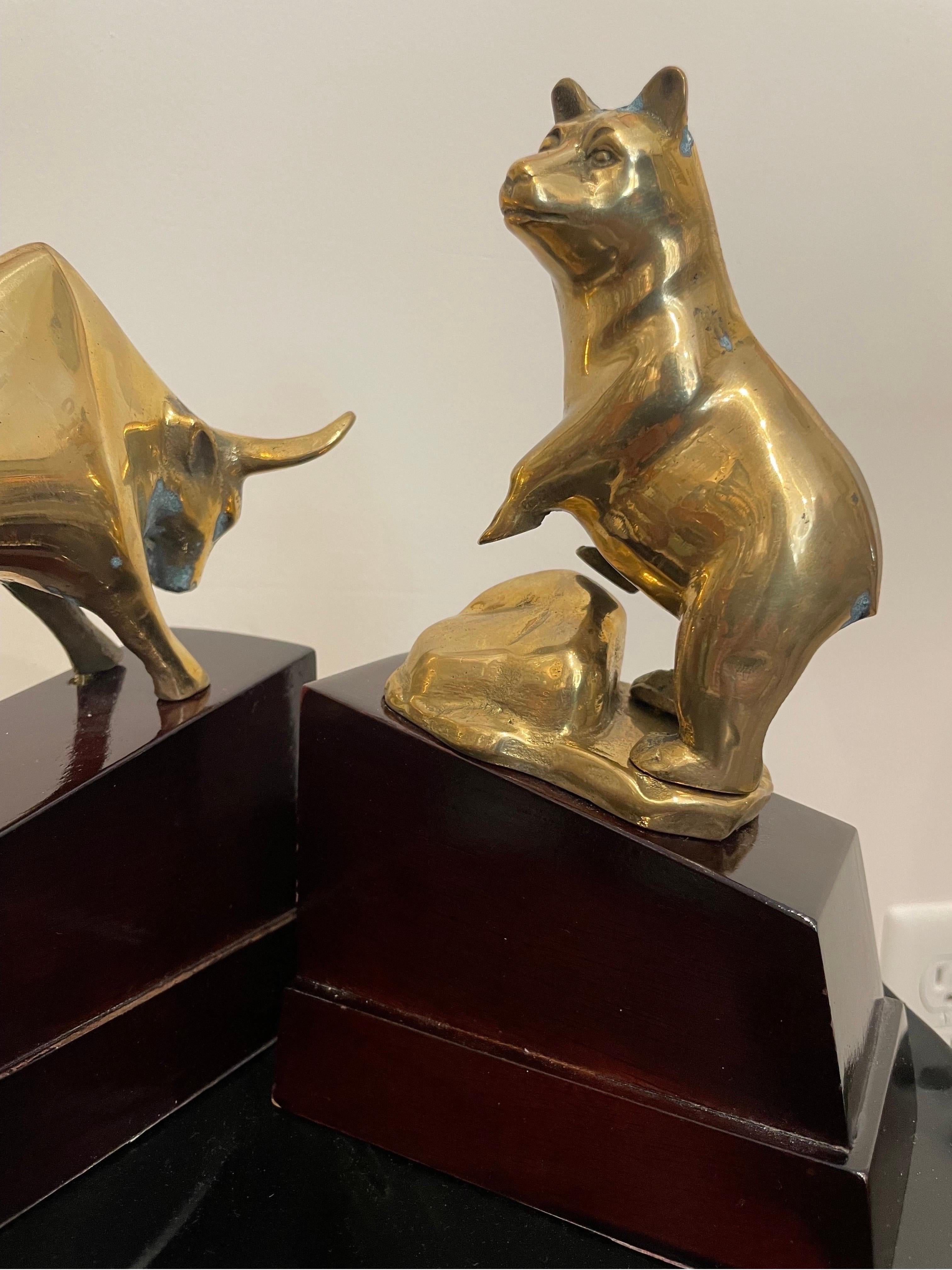 Vintage 1970's Classic Bear & Bull brass bookends on wood bases. The bull is in a charging position, while the bear is standing upright.