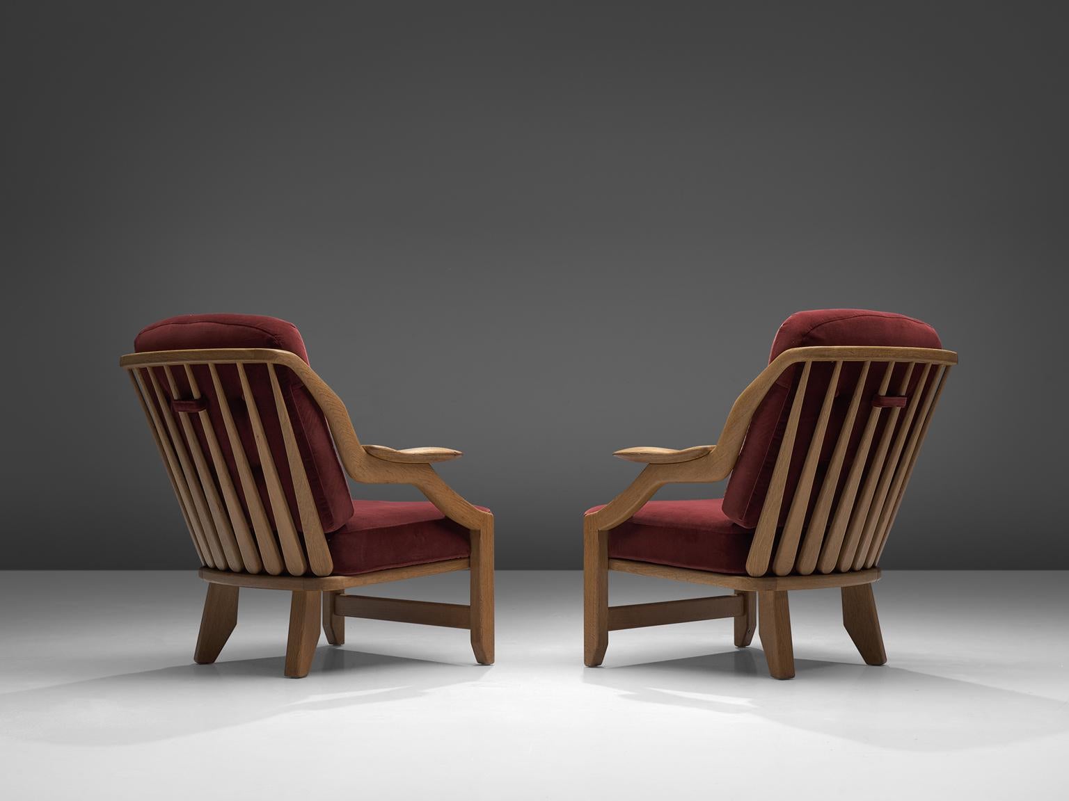 Guillerme & Chambron, pair of lounge chairs burgundy fabric and oak, France, 1950s.

This French designer duo is known for their extreme high quality solid oak furniture, from which this orange set is another great example. These chairs have a