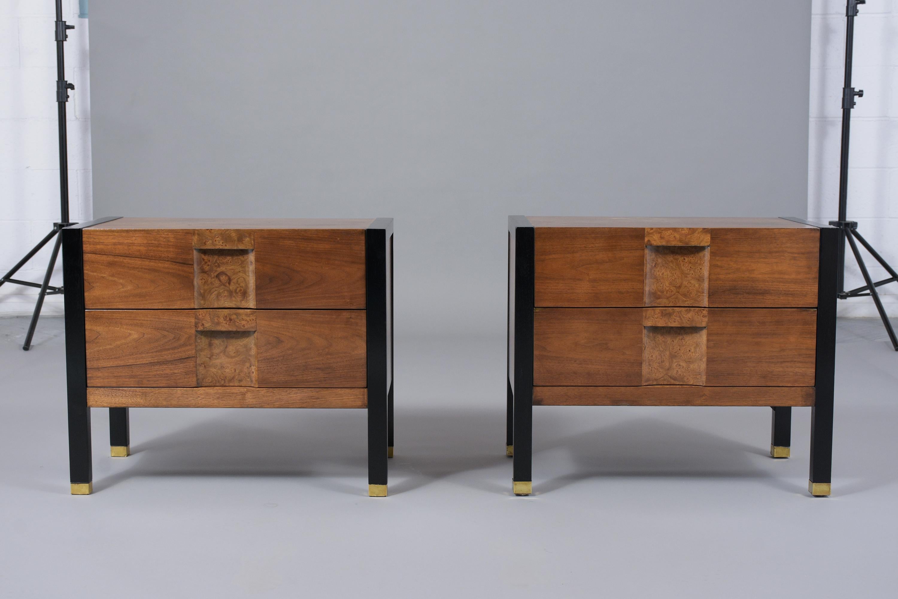 A remarkable Pair of Mid-Century Modern nightstands hand-crafted out of walnut features a new walnut and ebonized color with a lacquer finish and are professionally restored. The end tables have burled veneer details in the center of the two drawers
