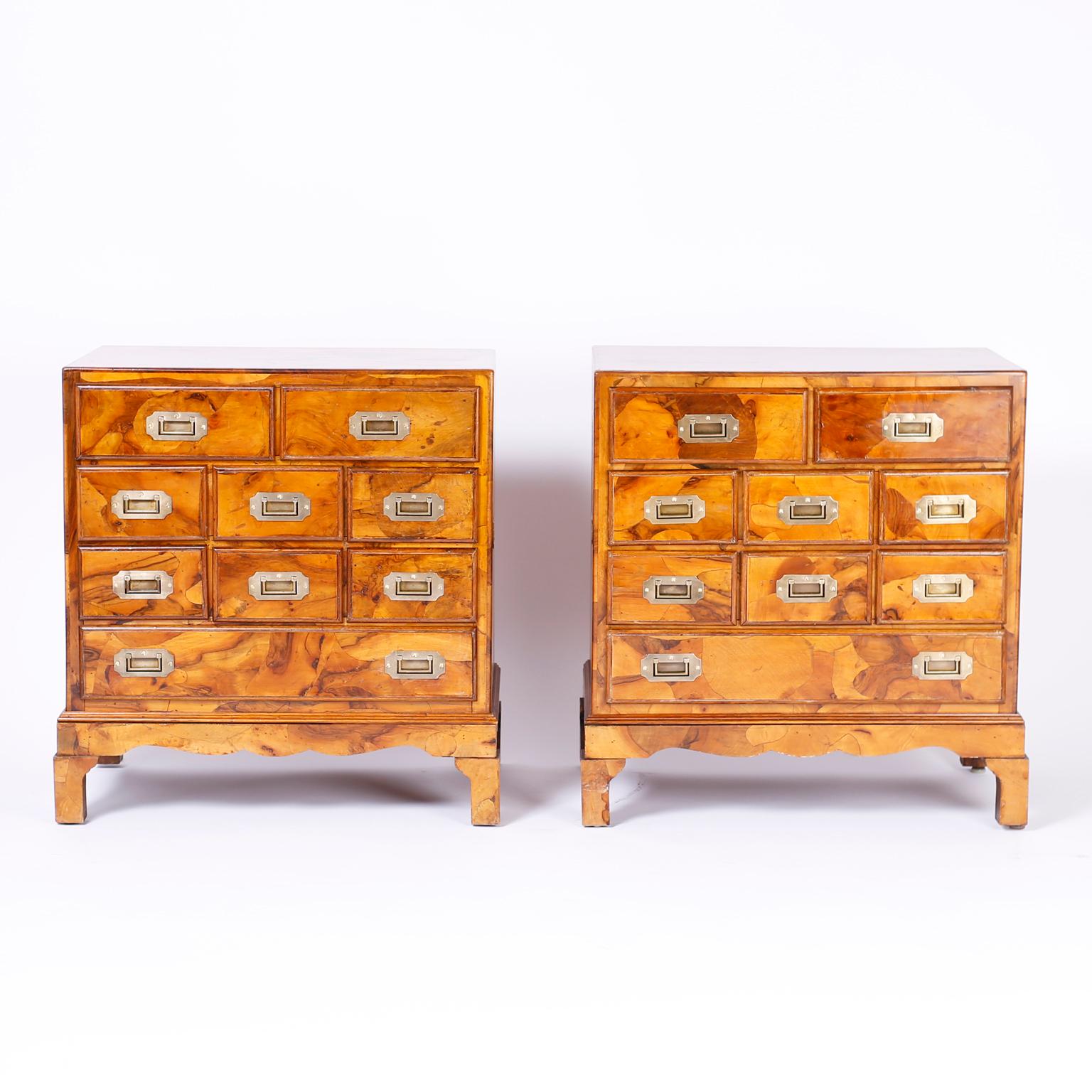 Pair of midcentury Italian nine drawer campaign chests with a stylized Queen Anne form, campaign brass hardware, and featuring a distinctive veneer technique that joins patches of bleached burled walnut into an unusual organic composition.