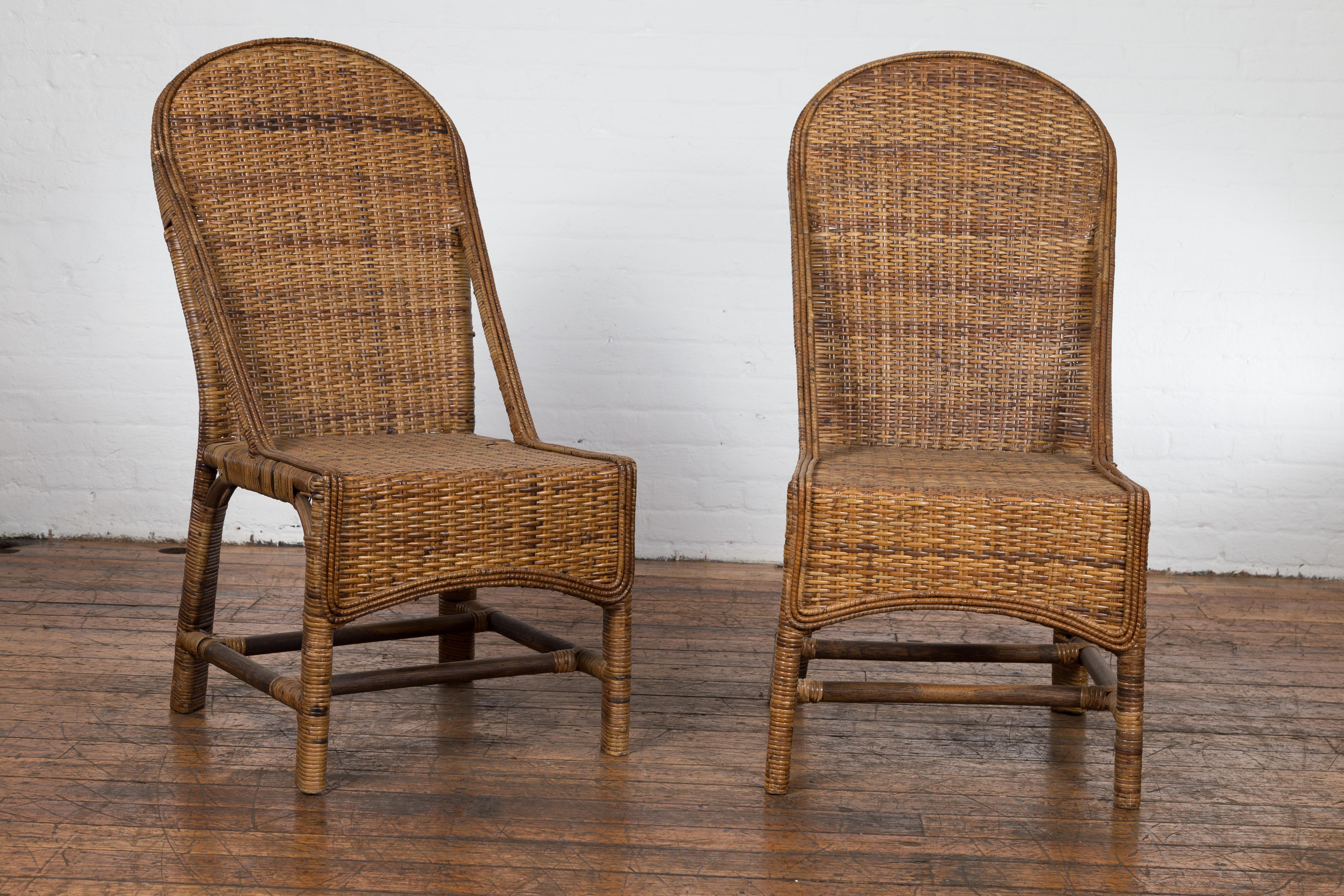 A vintage pair of Country style Burmese hand woven rattan chairs from the mid 20th century, with arching backs and double H-Form cross stretchers. Created in Burma (nowadays called Myanmar) during the midcentury period, this pair of rattan chairs