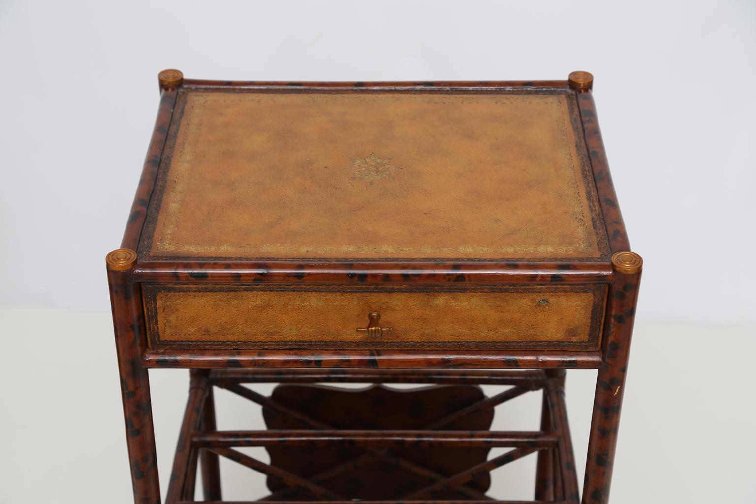 Pair of end tables or bedside nightstands, of burnt bamboo with tortoise finish, each having a rectangular top of tooled leather with gilt decoration, matching sides, back and single frieze drawer, raised on four legs, joined by canterbury rack