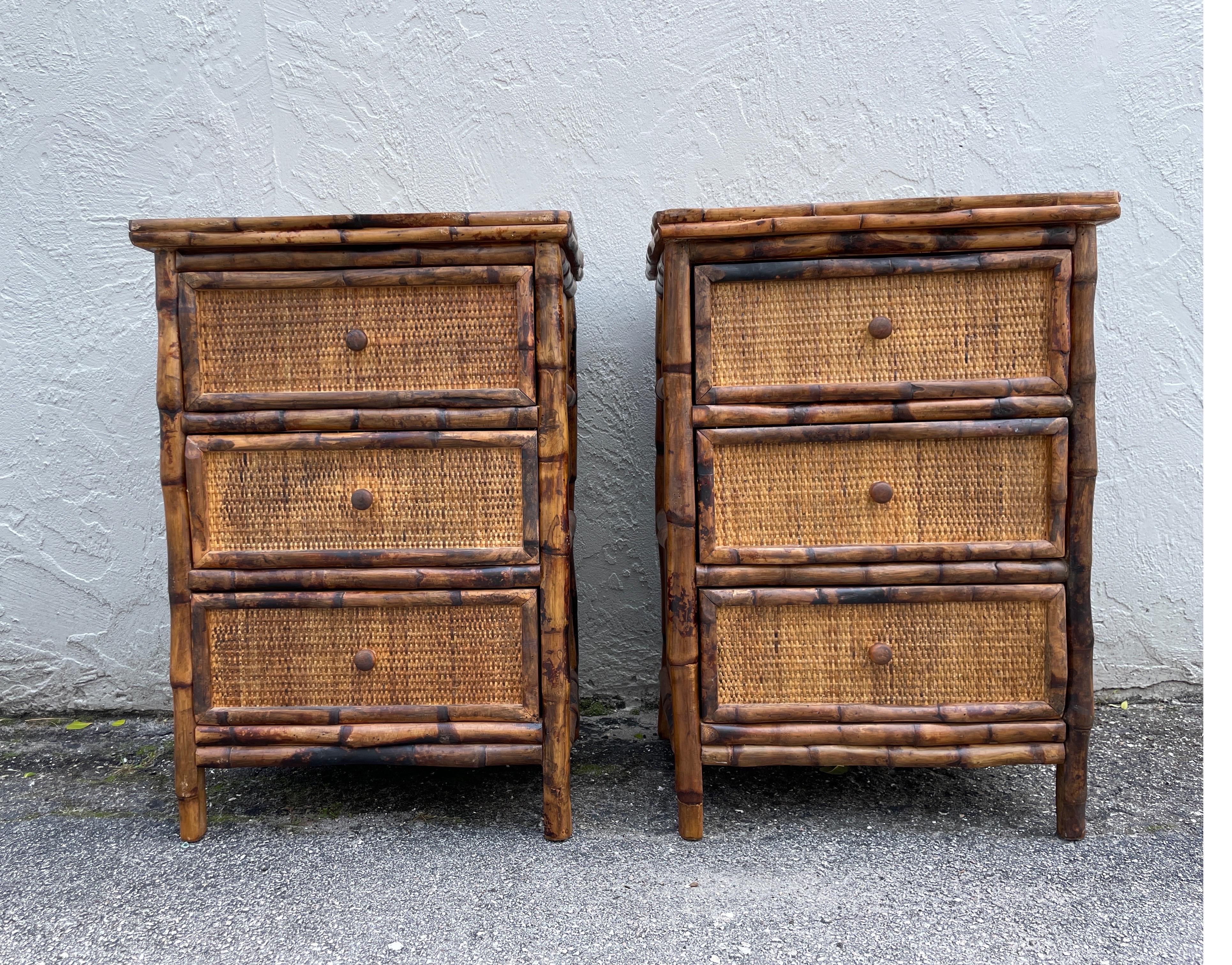 Vintage pair of burnt bamboo three drawer nightstands / side tables. The entire chest is covered in split bamboo including the back. The front of drawers is covered in raffia.