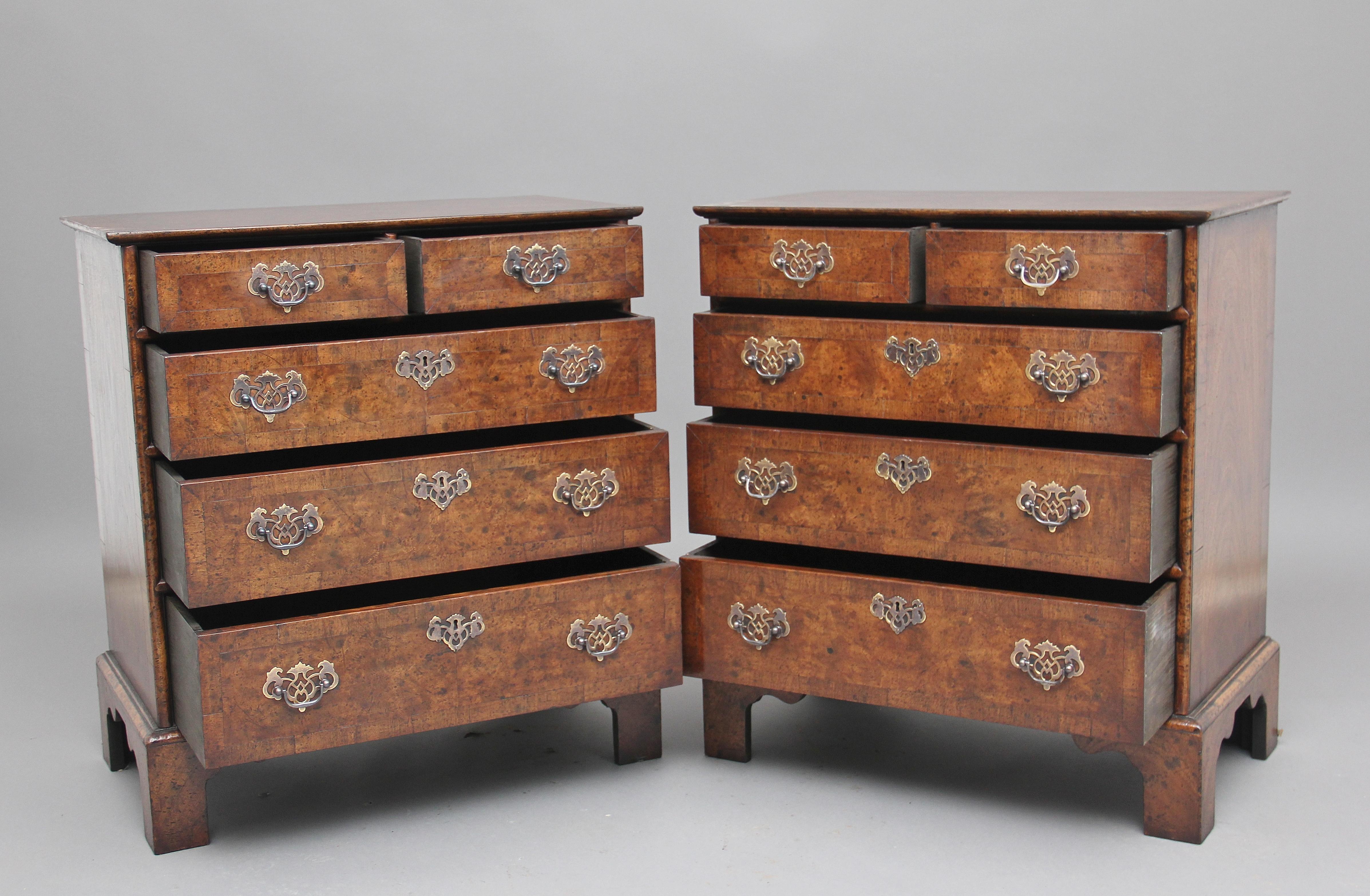 A pair of burr walnut chest of drawers in the George I style, the crossbanded quarter venered top above a selection of two short over three long graduated drawers, with pierced brass plate handles and escutcheons, the drawer fronts are also