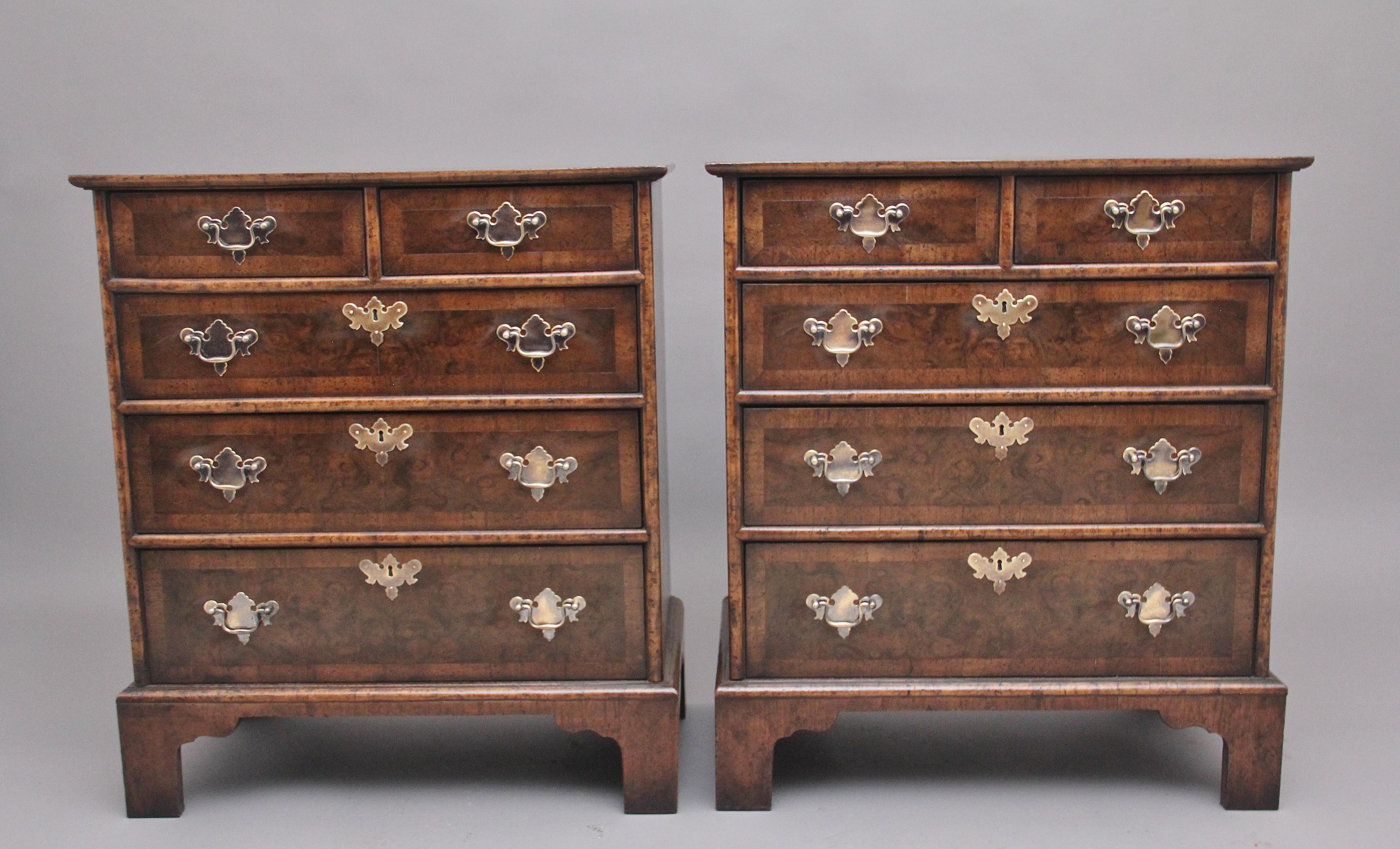 A pair of burr walnut chest of drawers in the George I style, the crossbanded quarter venered top above a selection of two short over three long graduated drawers, with brass plate handles and escutcheons, the drawer fronts are also crossbanded just