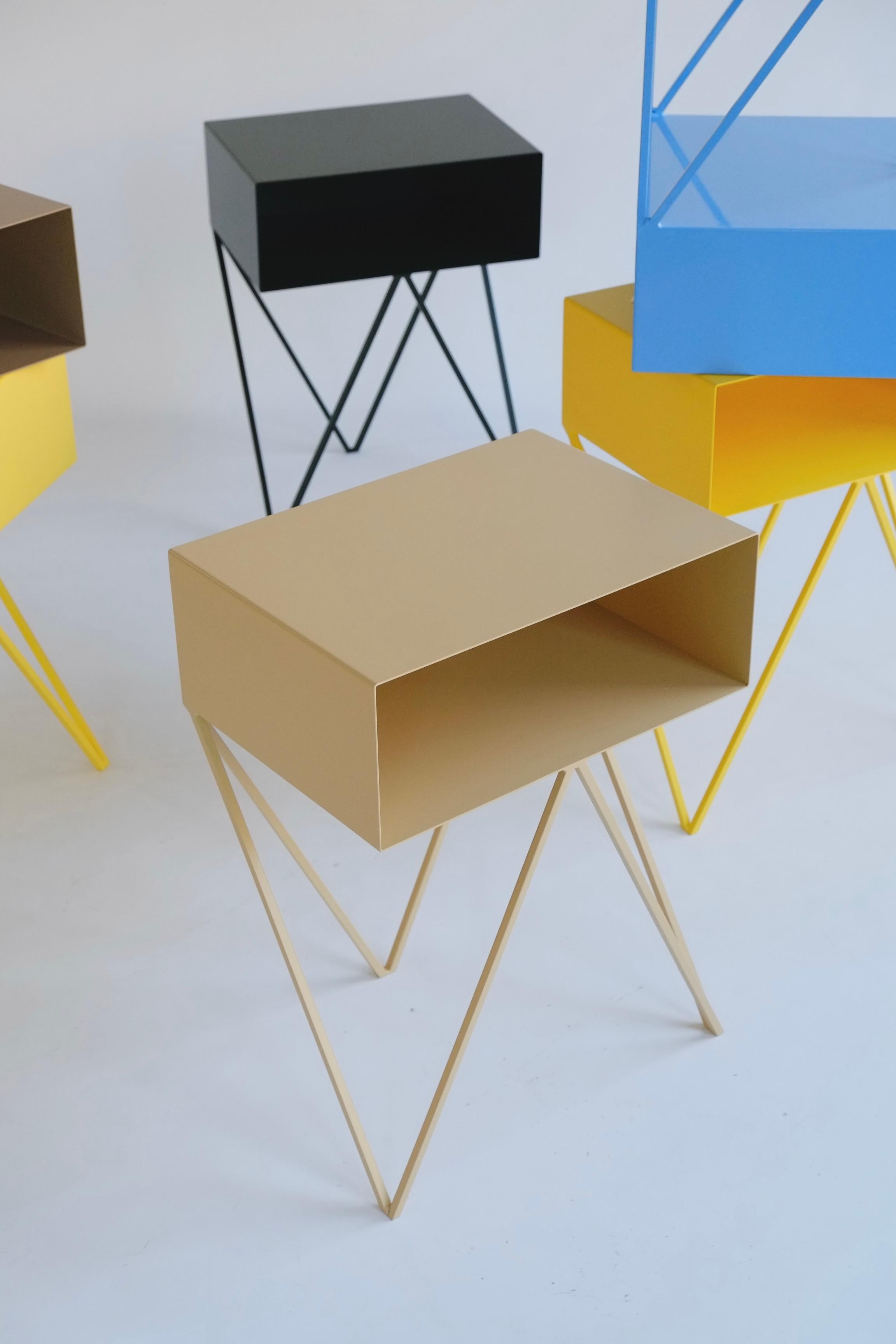 A beautiful pair of butternut beige Robot bedside tables. The Robot side table features an open shelf on zig zag legs. A fun and functional design made of solid steel, powder-coated in yellow. The clean lines look great against period details as