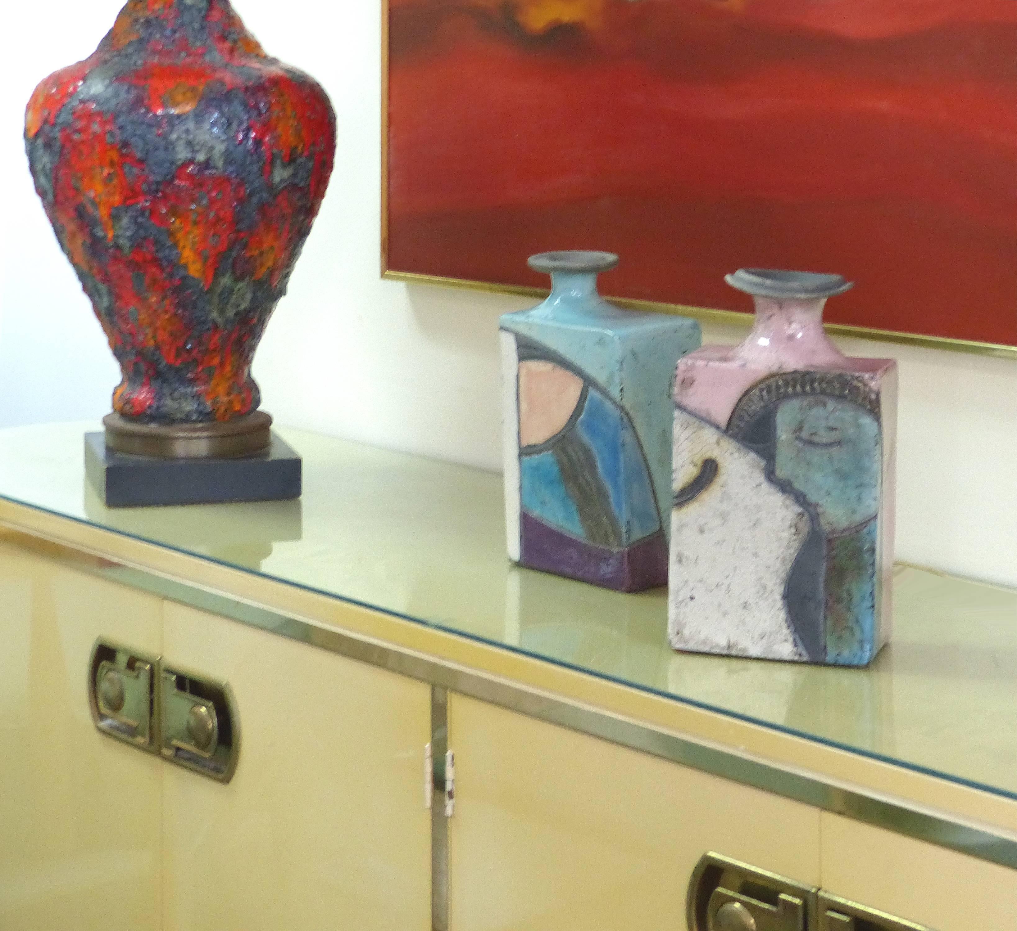 Offered for sale is a pair of hand bilt modern ceramic vases with incised and glazed abstract compositions. The vases each have complimentary decorations in rich hues and are signed within the designs on the sides. Their variations in size and