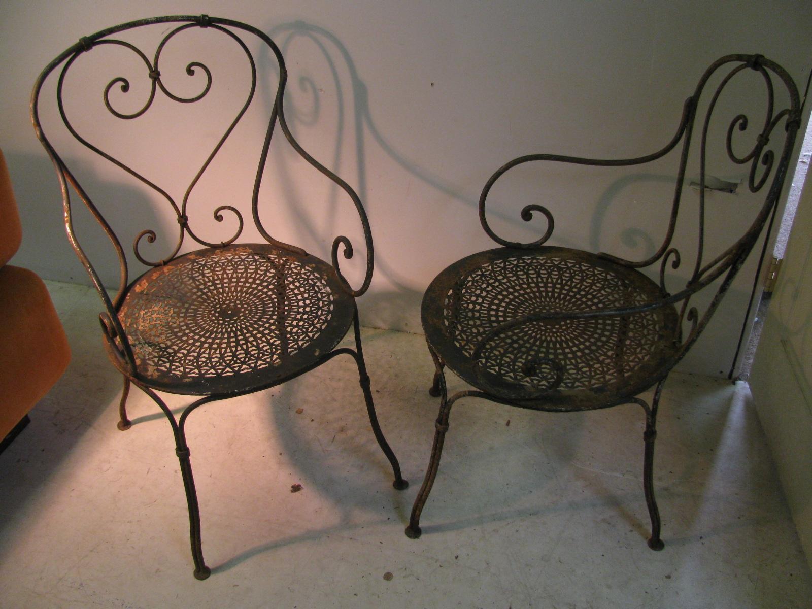 Fabulous pair of French garden chairs. Handmade wrought iron with heart shaped backs and pierced sheet metal seats. Excellent construction methods with iron wraps tying sections together. Seat is riveted.