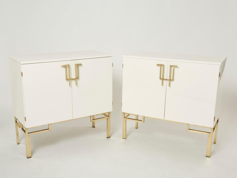 A very rare pair of vintage Guy Lefevre for Maison Jansen cabinets bar made in the 1970s. Glossy white lacquer, paired with bright brass asian inspired handles end feet, feels crisp and luxe. Featuring 2 doors and an opening top, they used to be
