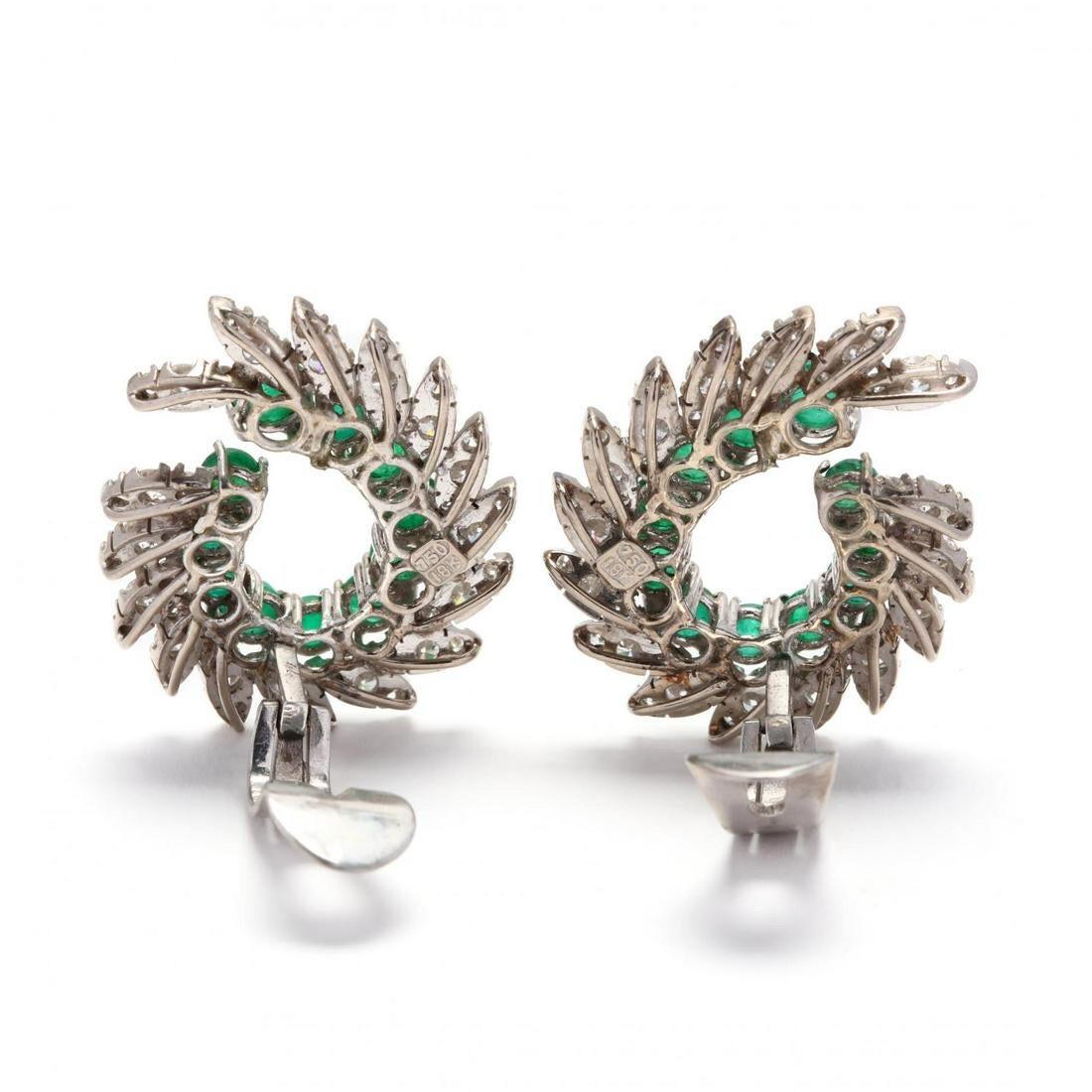 An elegant and impressive large pair of 1960's emerald and diamond clip earrings in a dramatic, swooping swirl shape. 

The earrings crafted of 18K white gold studded with cabochon emeralds weighing approximately 8.82 total carats, and surrounded by