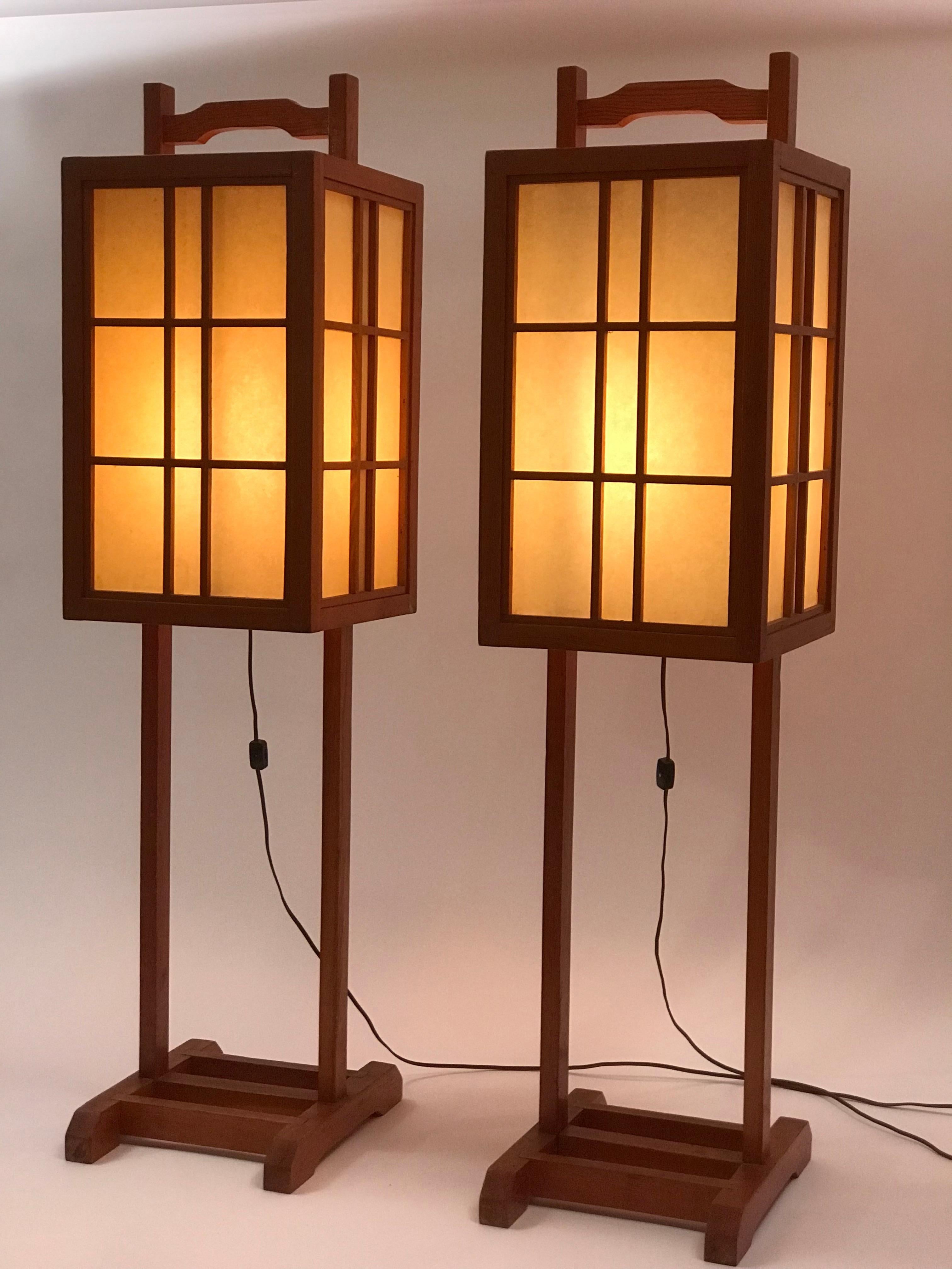 A pair of Japanese inspired wooden floor lanterns with pagoda style framing and a textured vellum amber toned diffuser. Hand made in California probably in a Valley/Van Nuys studio from the late 60's through the mid 70's. Framed in a local softwood
