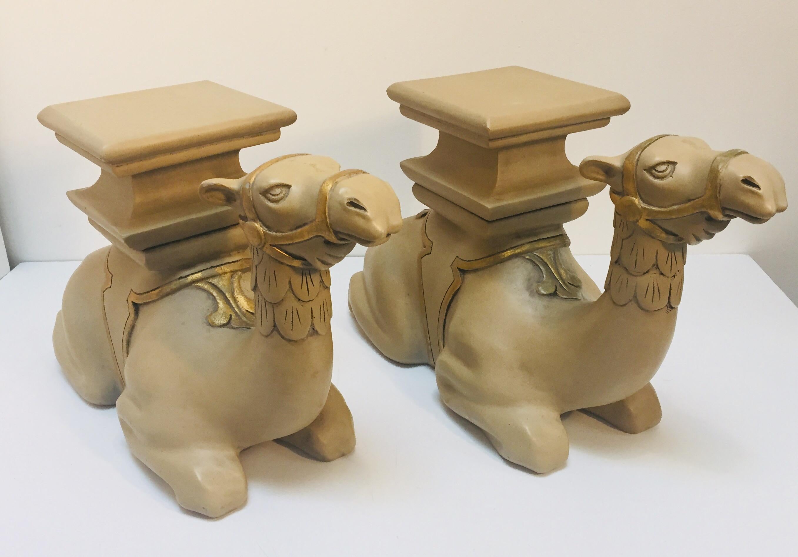 Pair of decorative Moroccan kneeling camel sculptures to use as stools or side tables.
1950s wood carved camel sculptures, USA, 1950s.
Beautiful sand color with gold details, these stools could be use for plant Stand, stools or side tables.
Will