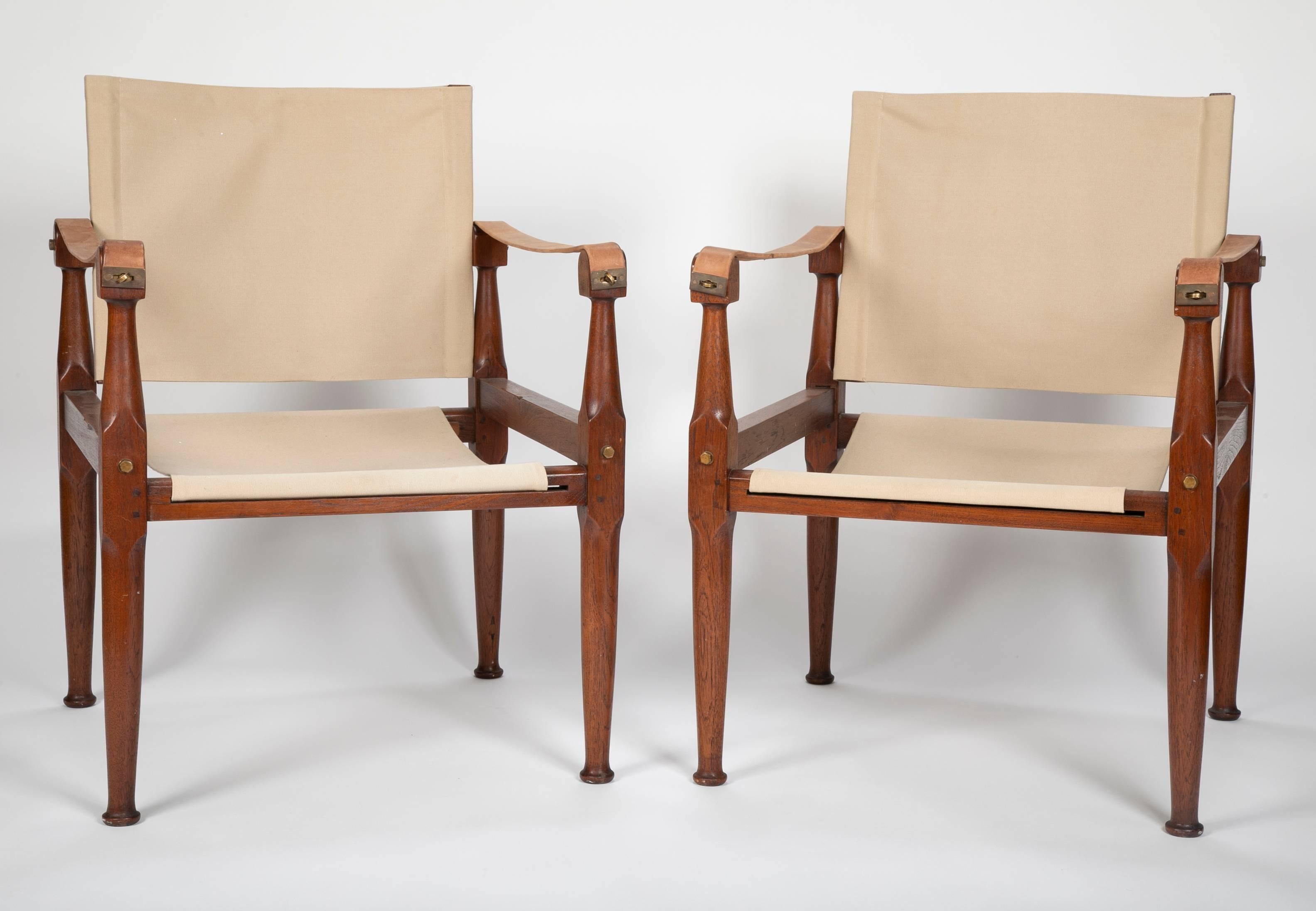 A pair of teak campaign chairs in the style of Karre Klint. Chairs have canvases seats and brass hardware. Ready to be placed.