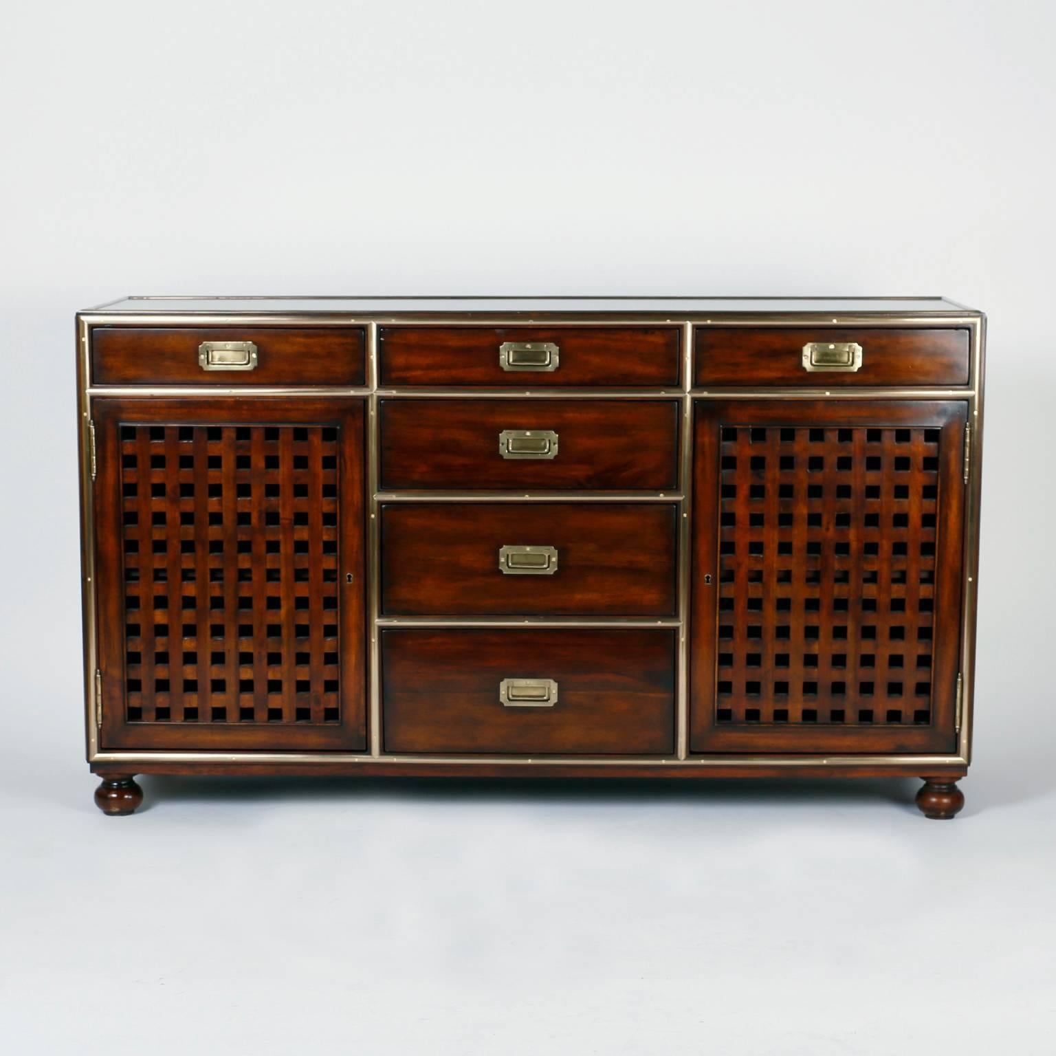 Fine pair of midcentury campaign style mahogany cabinets or servers with hand polished and lacquered brass hardware, six drawers, and two grated doors for plenty of storage. Signed Theodore Alexander on a brass plaque.