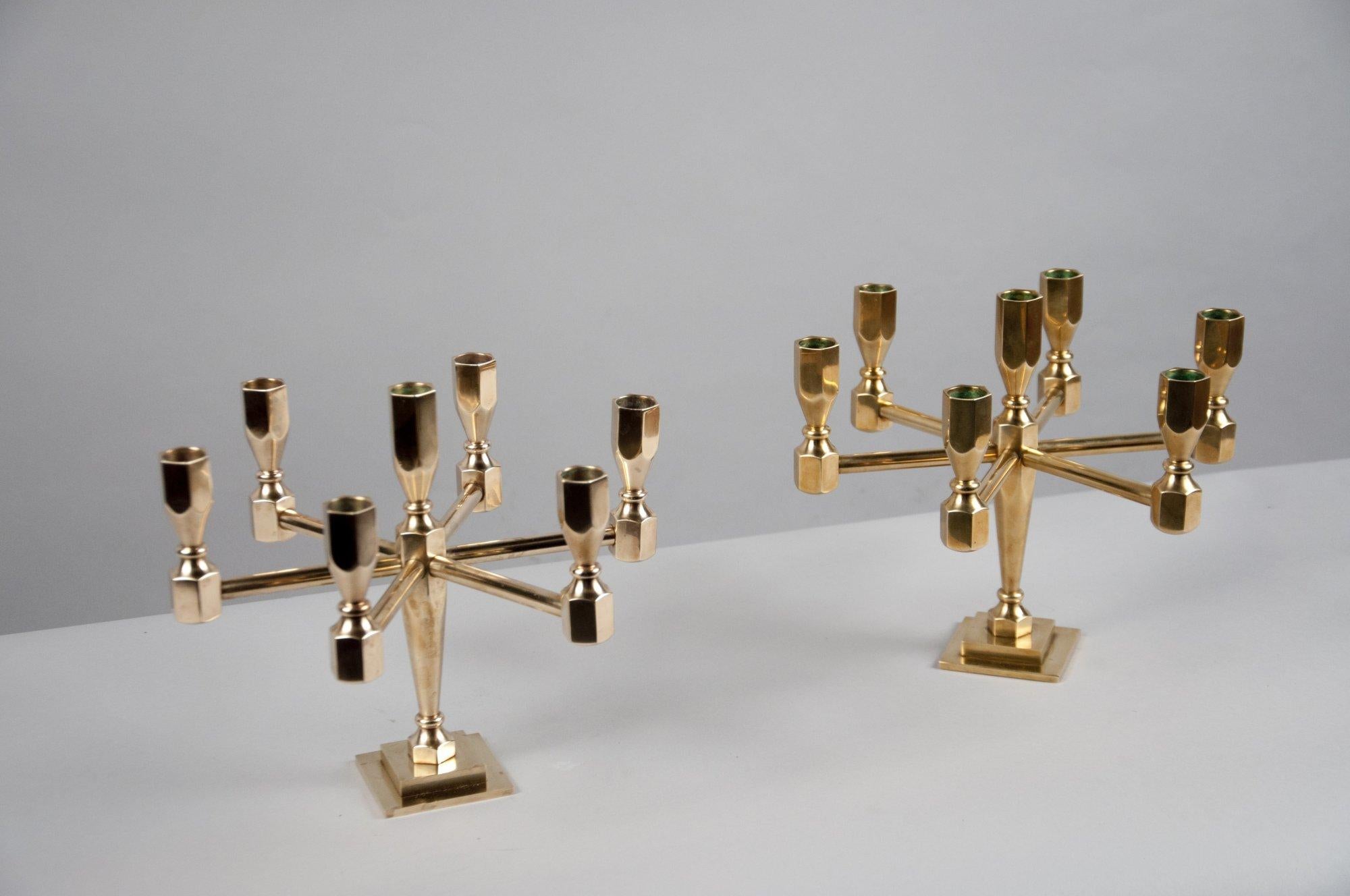 Pair of solid brass candelabra with six hexagonal candleholders radiating from a seventh slightly raised candleholder in the center, raised on a stepped square base.