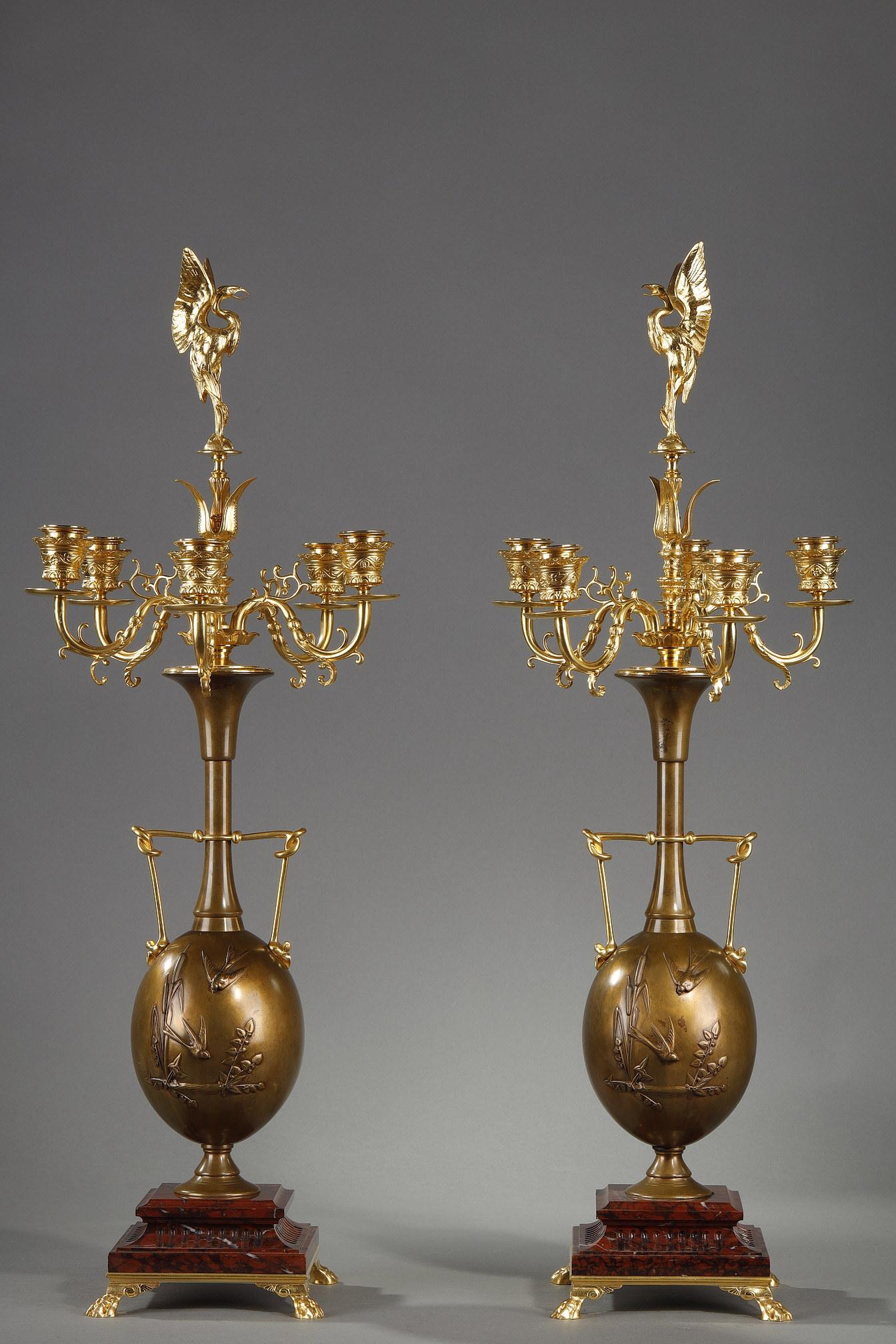 Paire de candélabres en bronze et bronzes signés Henry Cahieux (1825-1854) et Ferdinand Barbedienne. Le fût en forme de vase à deux anses est décoré d'oiseaux parmi des branches, d'où s'échappent quatre bras de lumière en bronze doré surmontés d'un