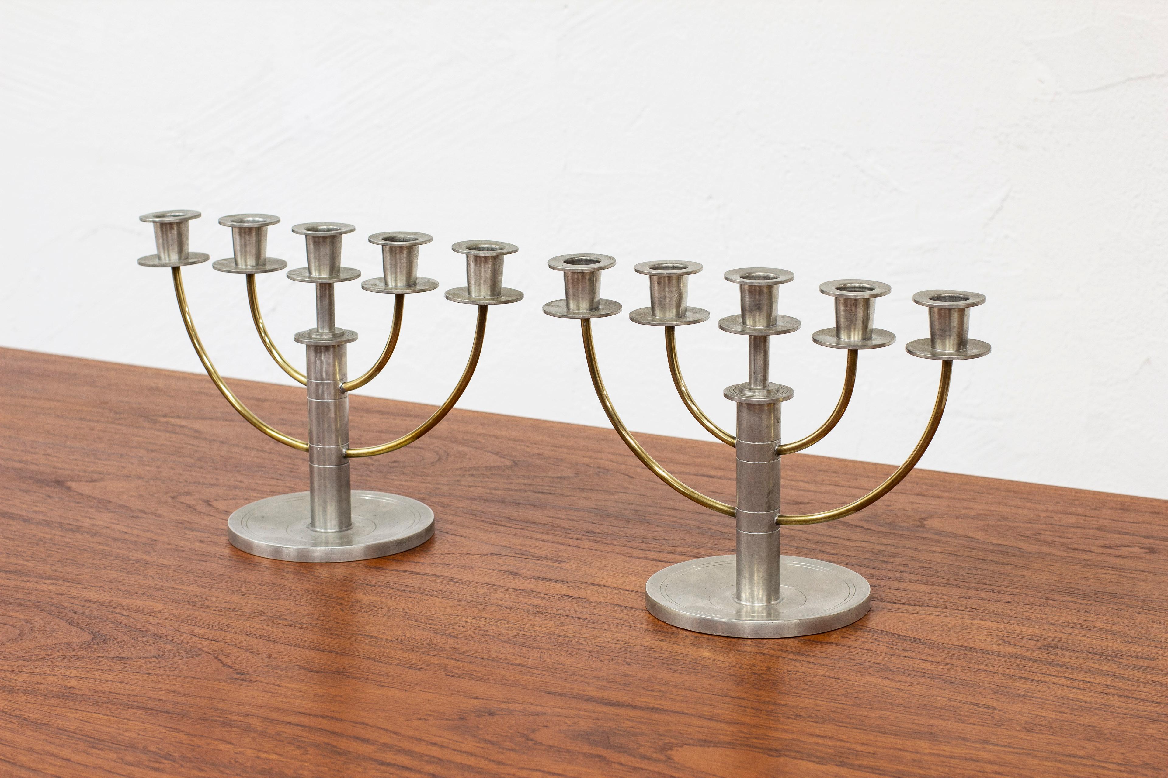 Pair of candelabras by C.G. Hallberg. Produced in Stockholm, Sweden 1933. Made from pewter and brass. Good vintage condition with age related signs of wear and patina. Signed with hallmarks. Saint Erik (Stockholm), CGH (CG Hallberg) and year stamp