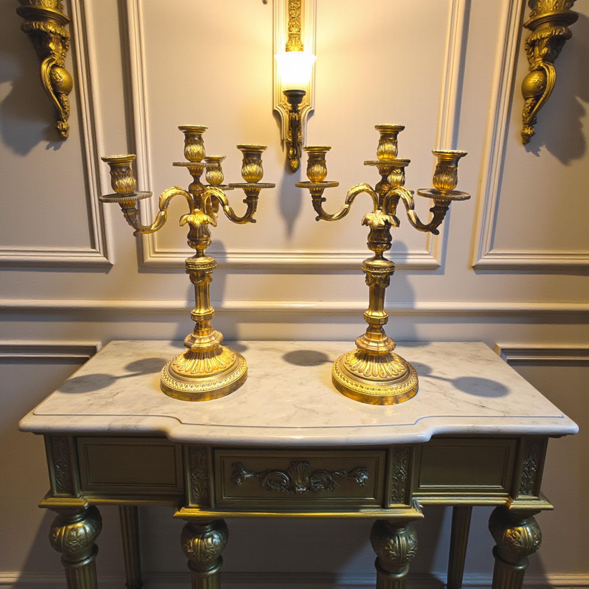Coppia di candelabri in bronzo dorato con tre bracci a spirale e un portacandele centrale, per un totale di quattro luci. Realizzati in stile Luigi XVI, questi candelabri presentano una splendida decorazione di foglie d'acanto, ghirlande e foglie