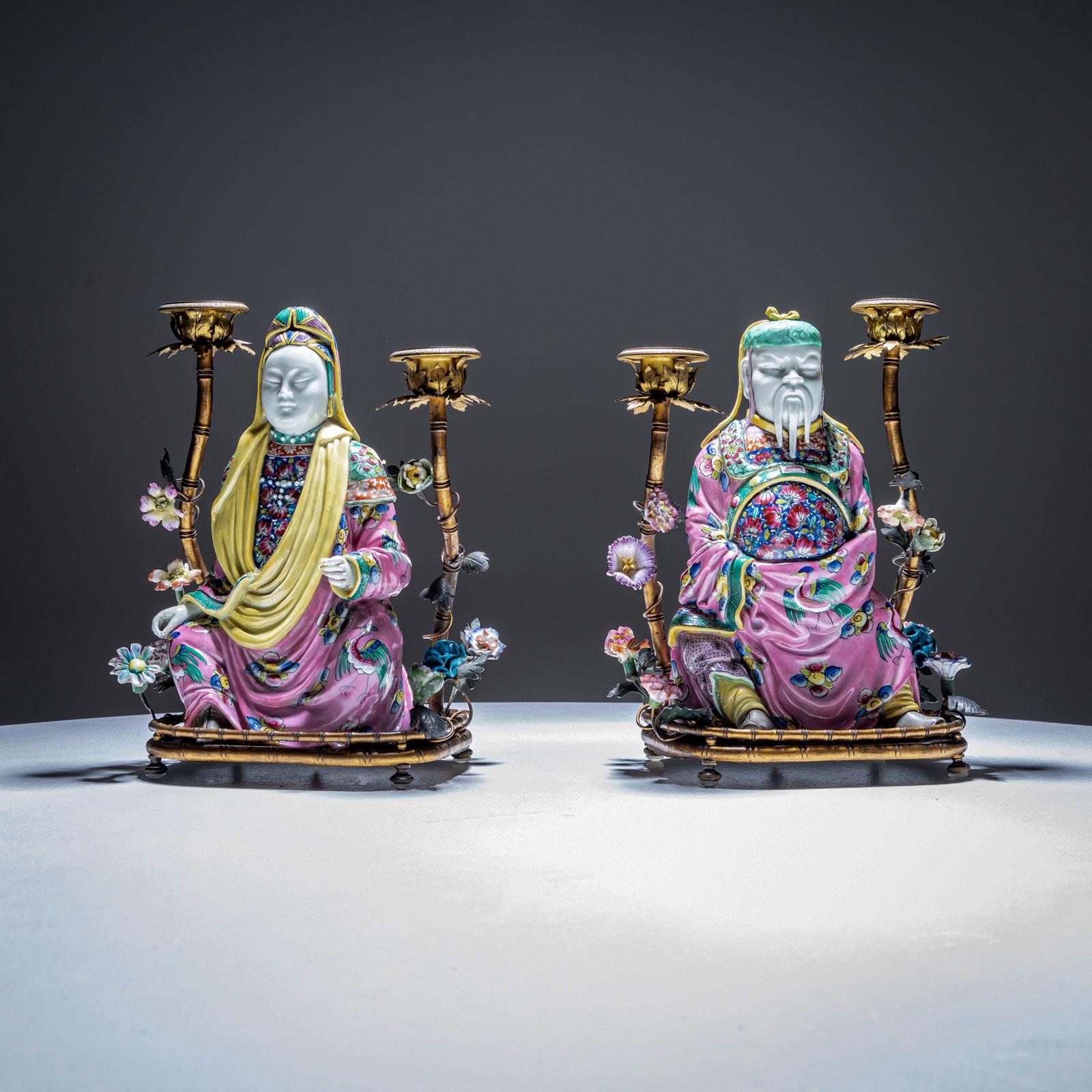 A pair of Famille Rose table candlesticks with a male and female chinoiserie figure sitting on a plinth in the shape of bamboo. The plinths are French, circa 1820.