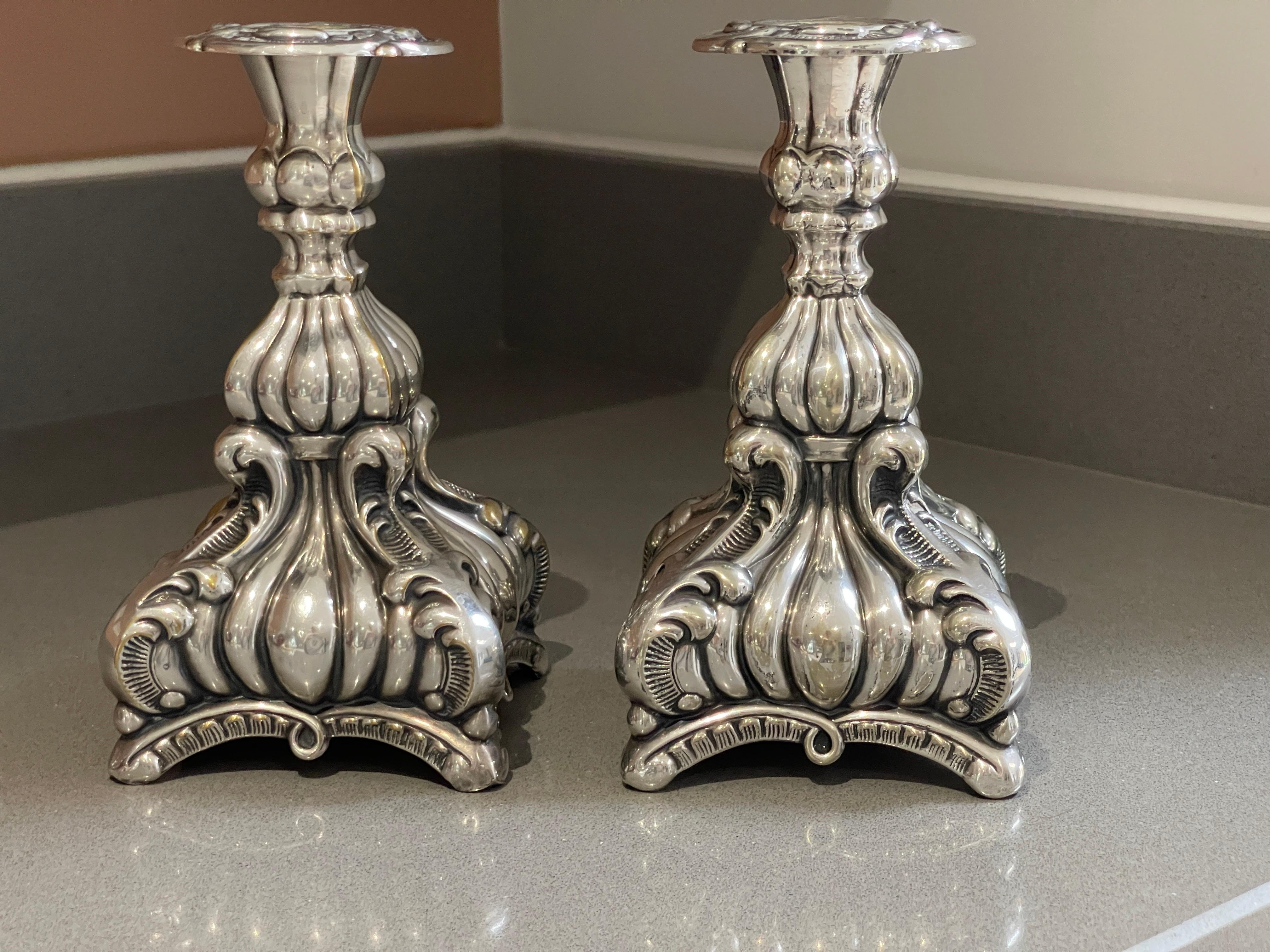 Antique silver, a pair of Rococo-style silver candlesticks, pressed, cast and chased. Circular, curved feet with hinged. Tested with the scratch test, height approx. 23 cm, diameter 10 cm. All-encompassing C-curves in relief, latticework, rocailles,