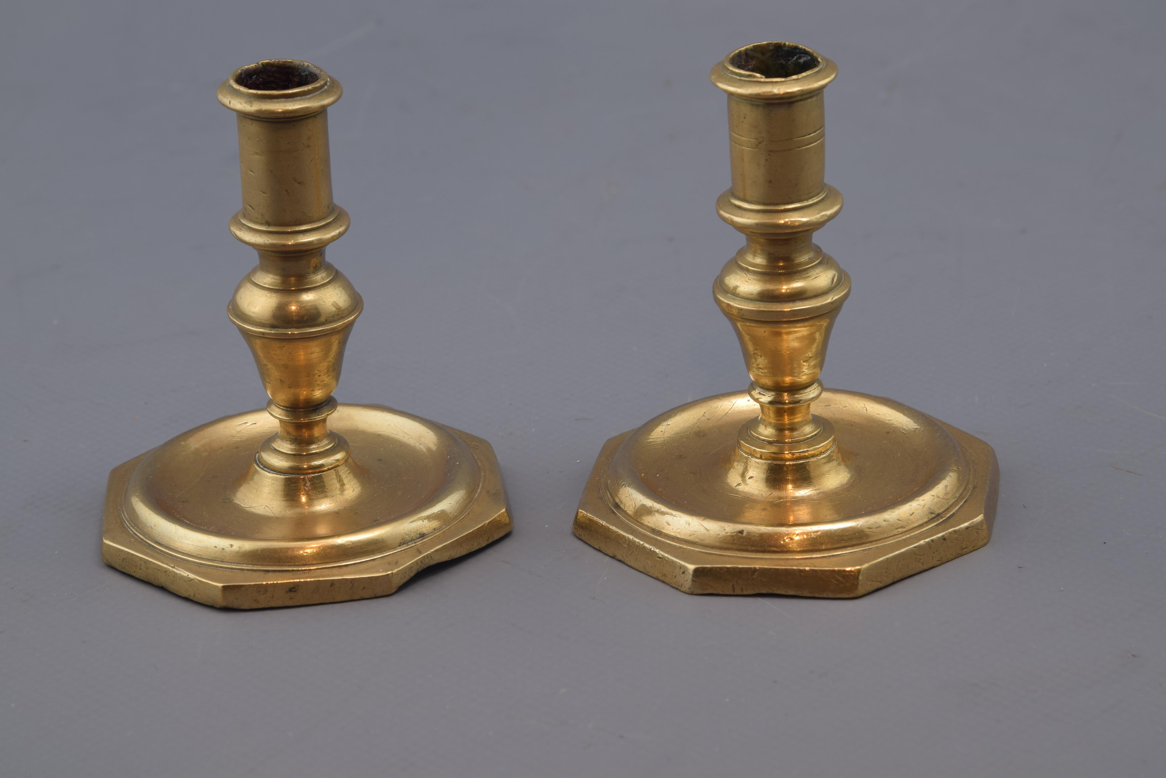 Pair of candlesticks with polygonal base in which is placed a smooth semi-circular molding, creating a projection that visually joins this exterior with the center; in the foot there are also other smooth moldings, combining projections and