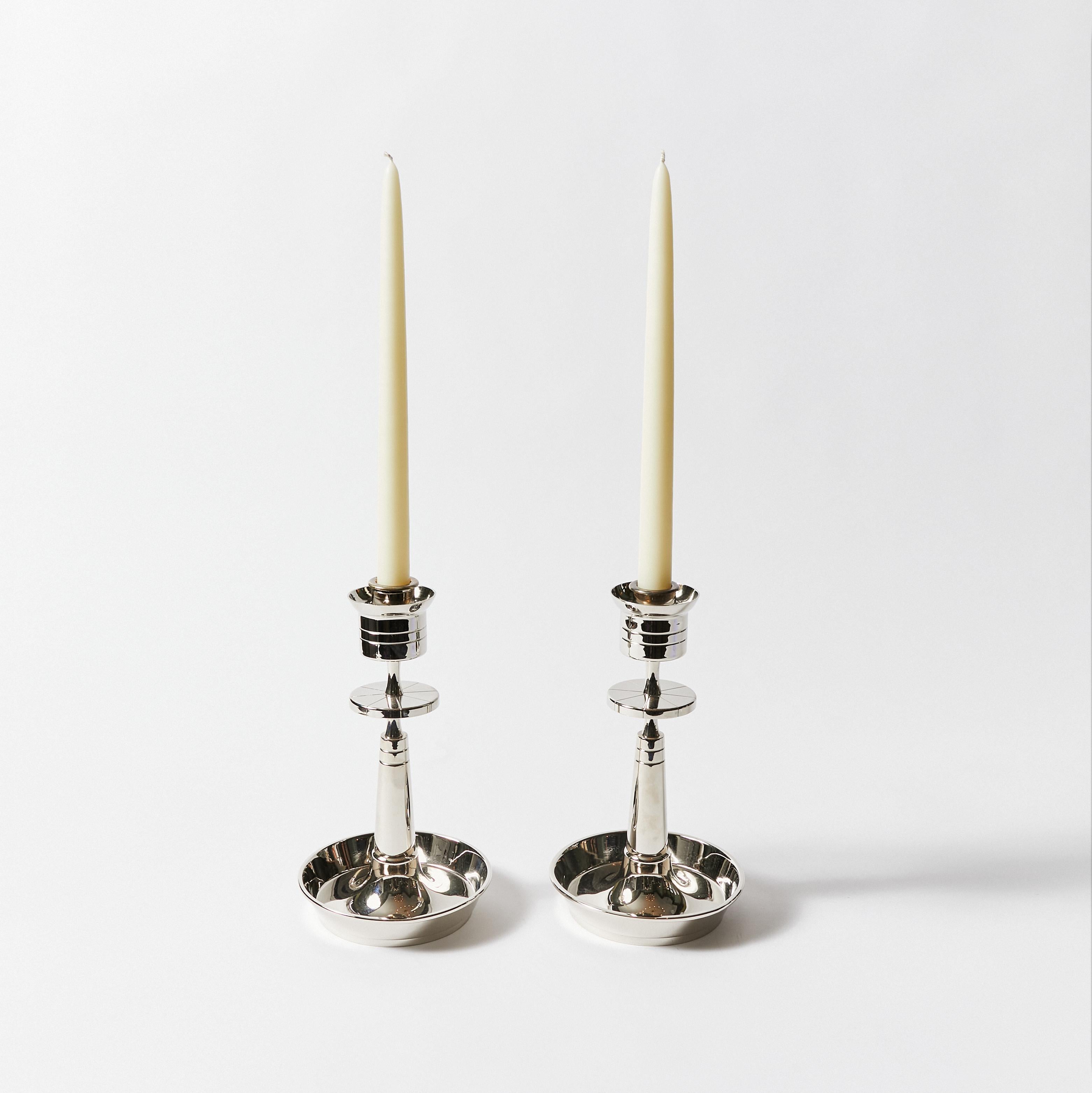 Set of two silver plated candle holders with a circular saucer base and a tapering candleholder with engraved plate. Designed by Tommi Parzinger for Dorlyn-Silversmiths. Stamped on bottom.