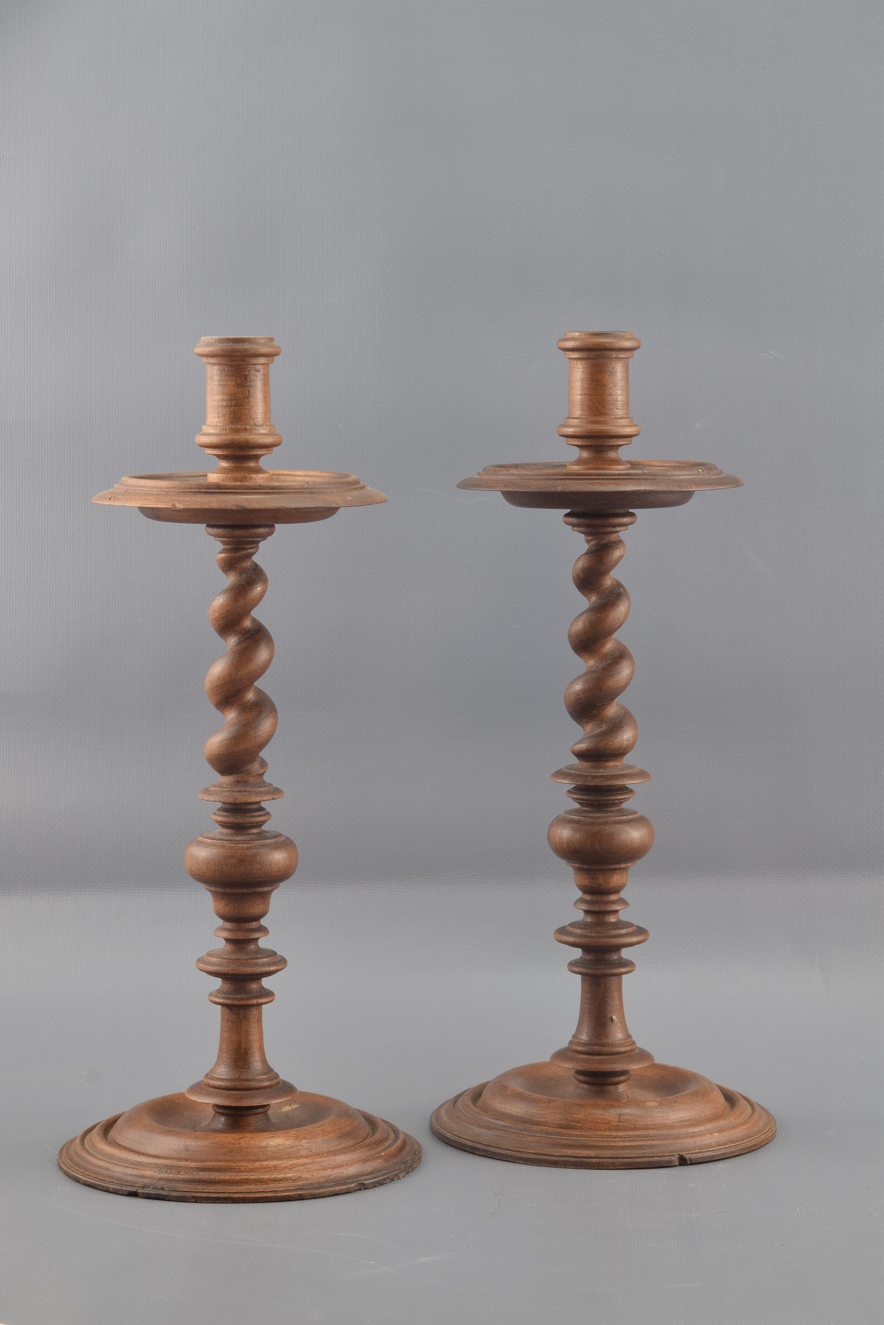 Each of the two candlesticks has a circular base decorated with a series of smooth moldings, an elaborate foot formed by discs, smooth areas, a knot in the shape of a vase and a shaft of Solomonic column and an upper part with a radio disc similar