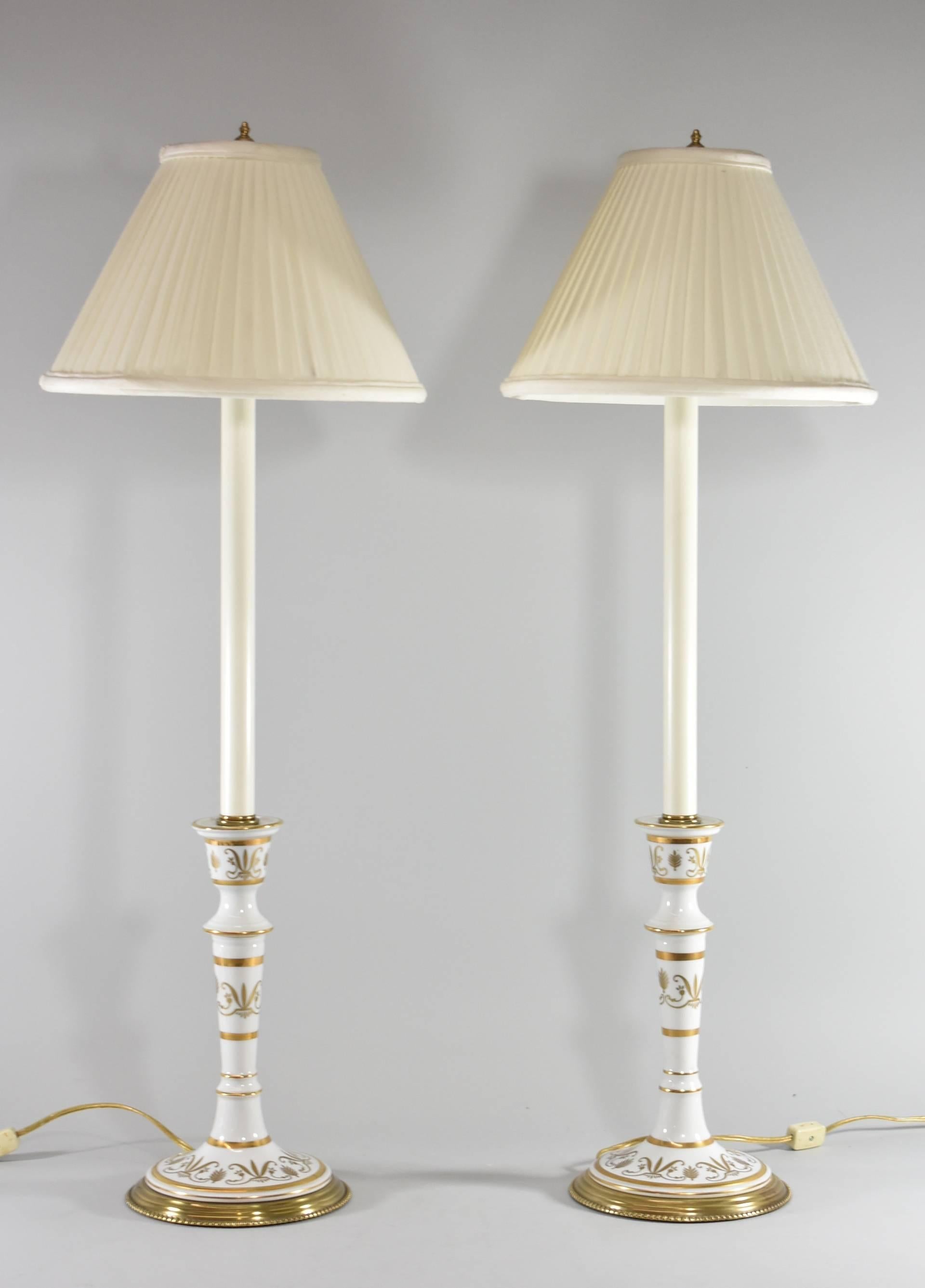 Pair of candlestick form porcelain and brass table/buffet lamps by Frederick Cooper. White porcelain base with gold highlight details on a brass base.