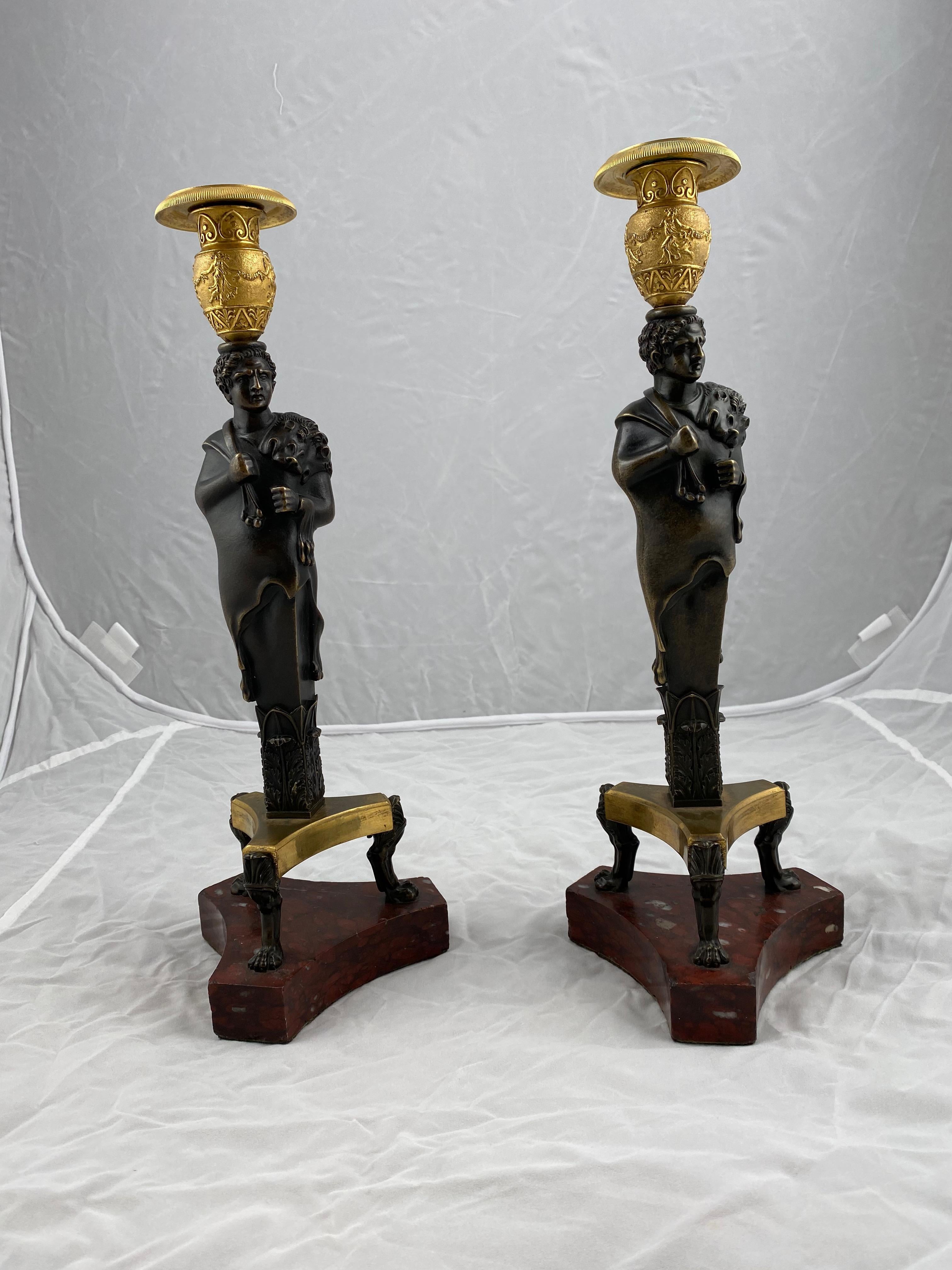 A magnificent large pair of candlesticks. The central part is made of dark patinated bronce. Napoleon depicted as Hercules, the Greek half god shown with a lion skin on his shoulder. The bases of red marble with cast bronce feet in the shape of lion