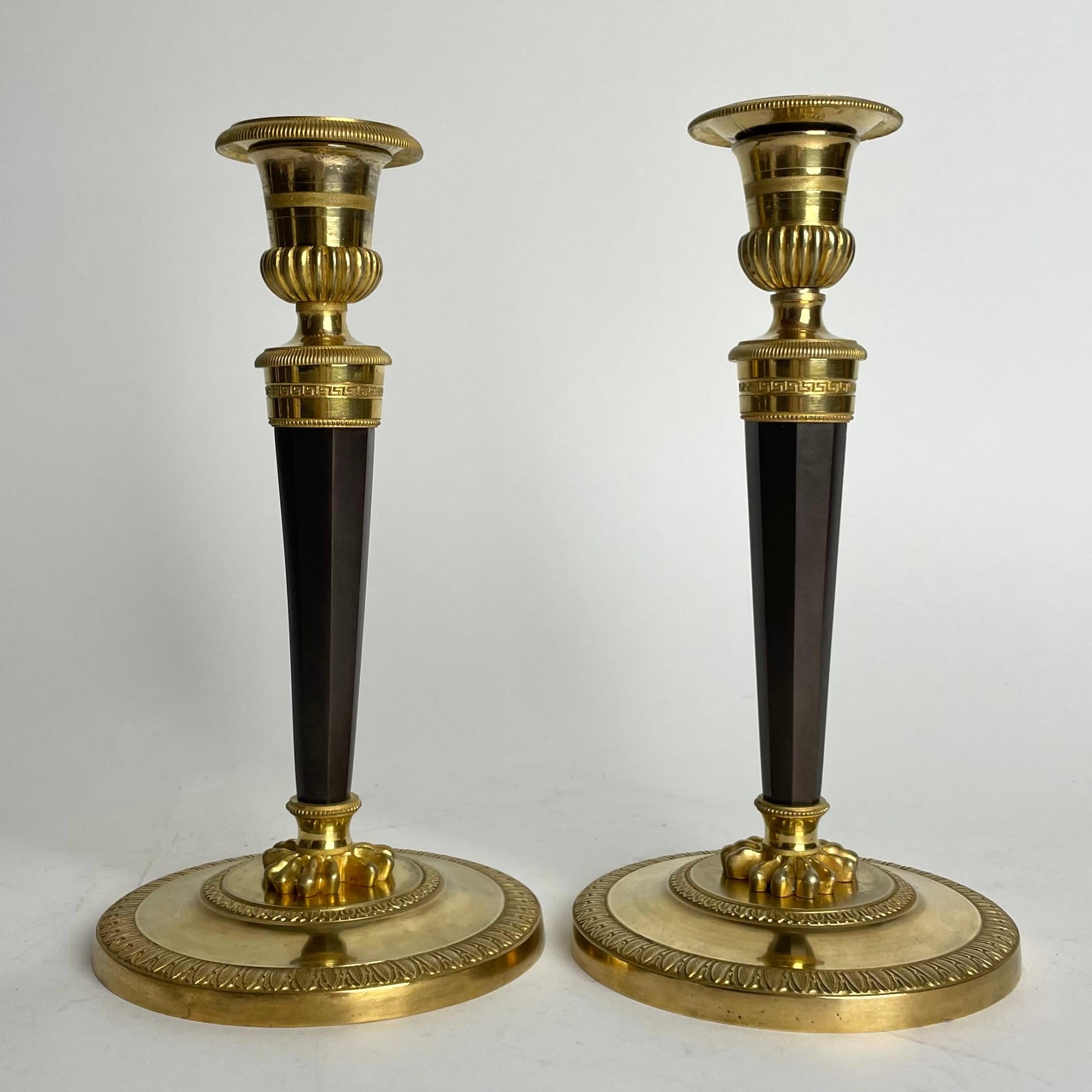 French Pair of Candlesticks in gilded and darkpatinated bronze. Directoire circa 1795 For Sale