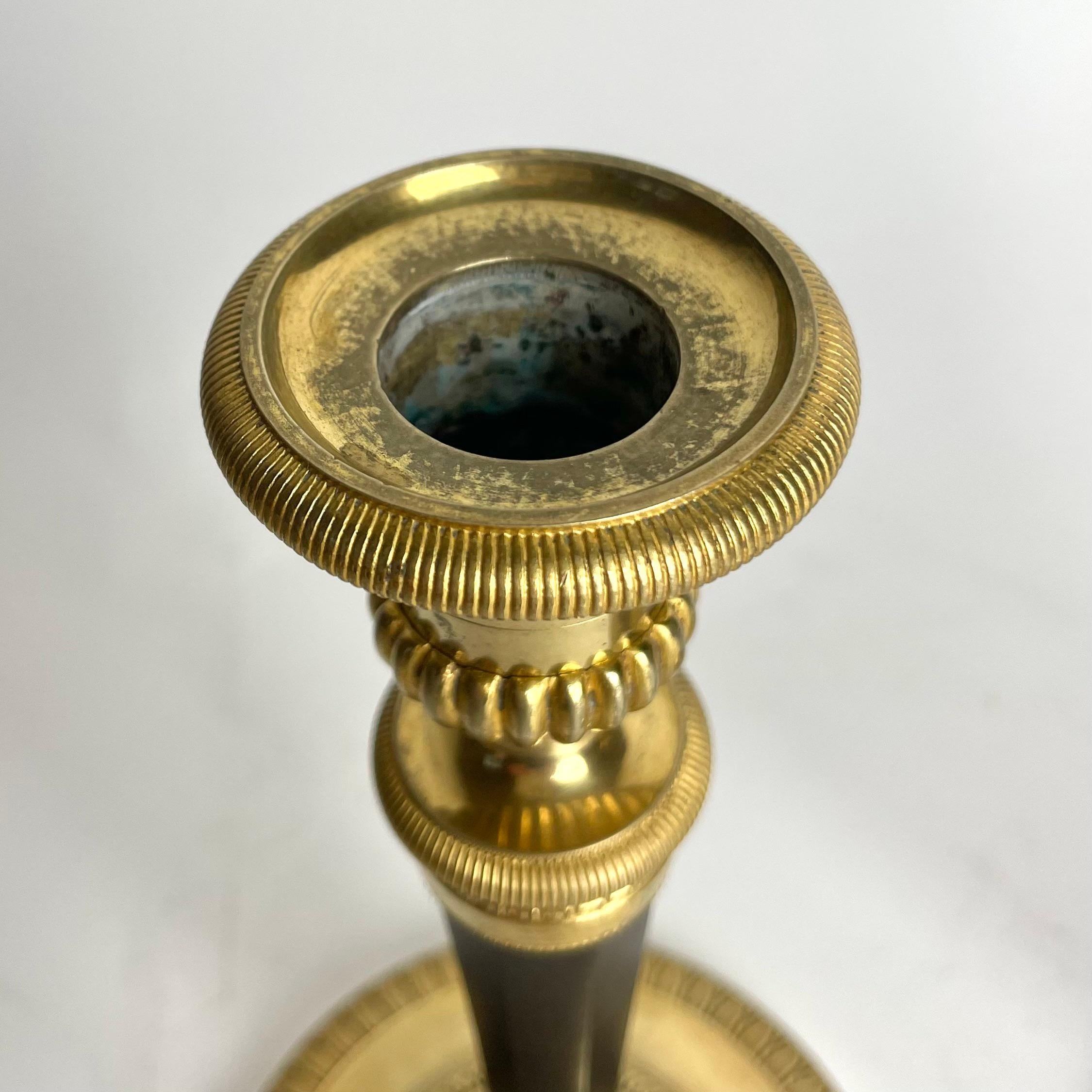 Bronze Pair of Candlesticks in gilded and darkpatinated bronze. Directoire circa 1795 For Sale