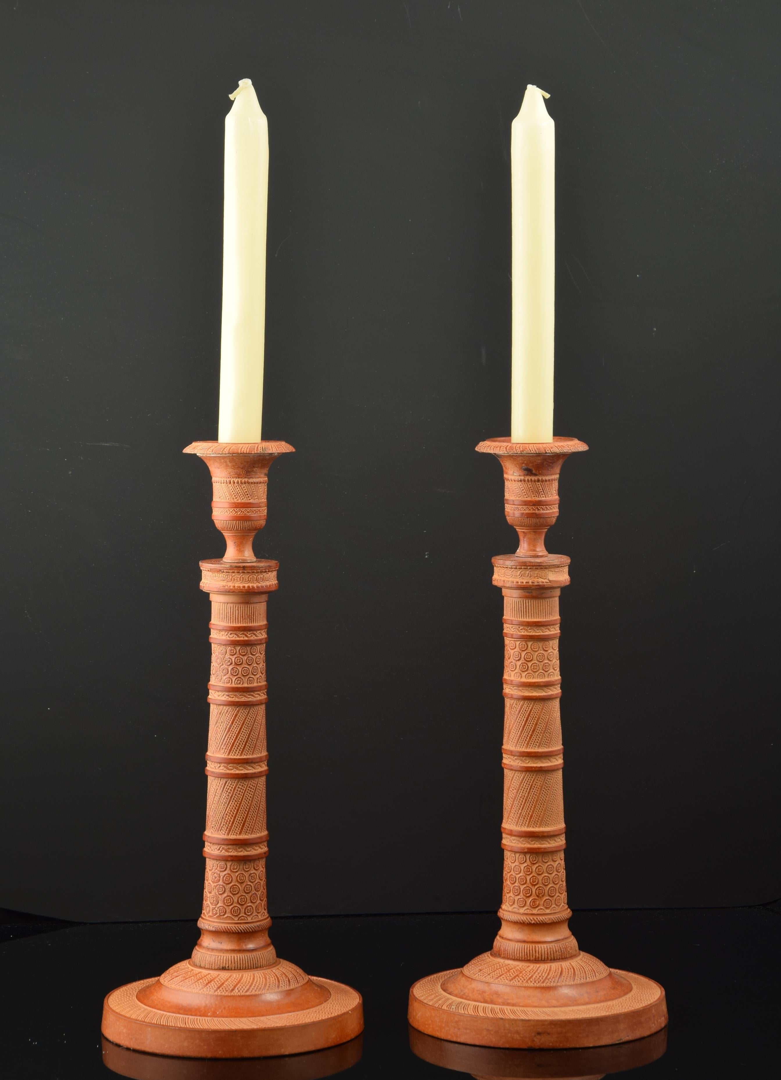 Paar Kerzenständer aus patinierter Bronze.
Einflammiger Kerzenhalter mit rundem Sockel, zylindrischem Korpus und Kerzenbehälter in Form einer klassischen Vase. Die gesamte Oberfläche ist mit Leisten verziert, die durch gerade Bänder mit