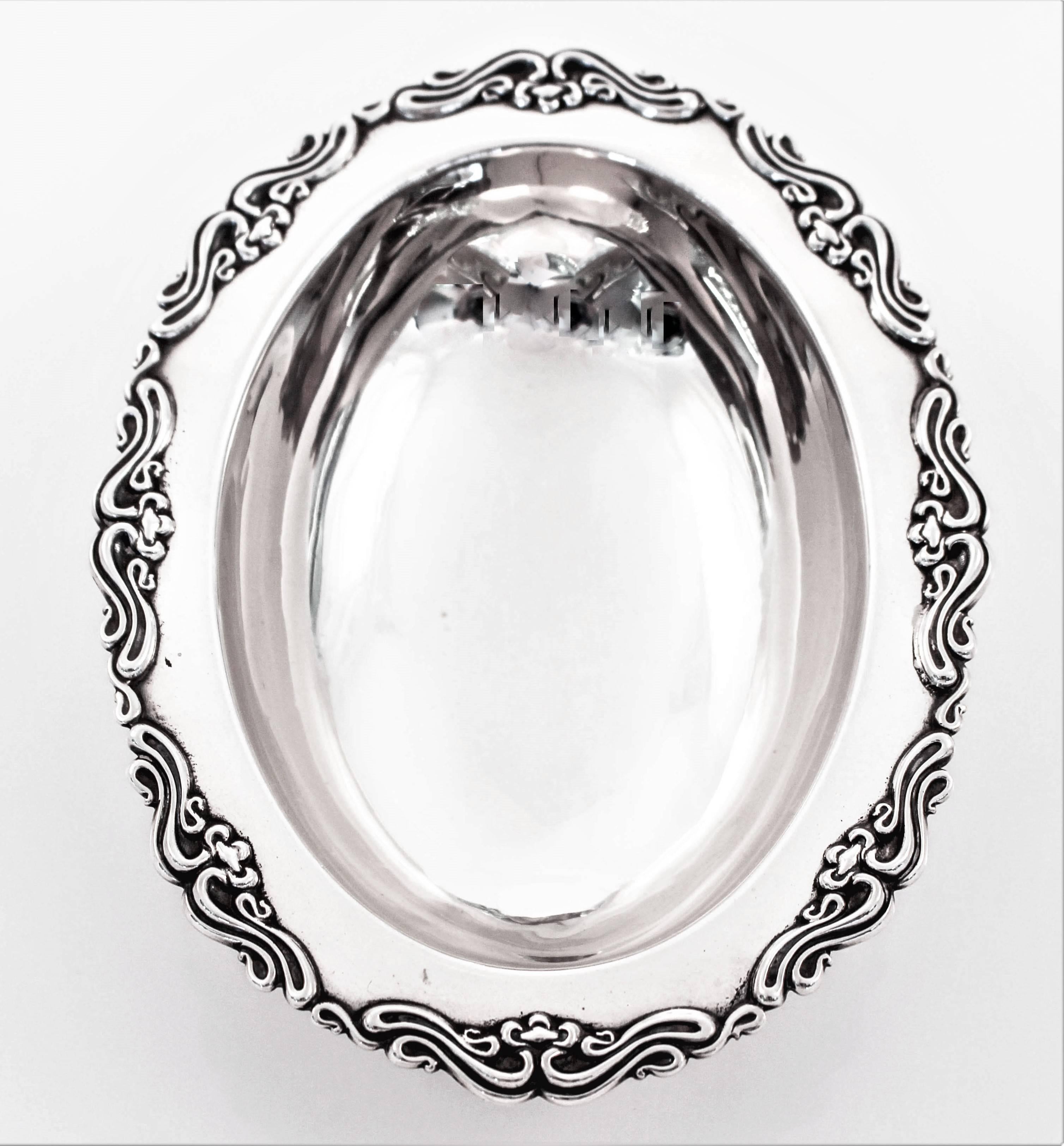 A pair of candy dishes with scalloped edges and four claw feet. These oval dishes have Art Nouveau raised -work around the edge and an oval shape. They are raised off the surface and have a deep centre.
  