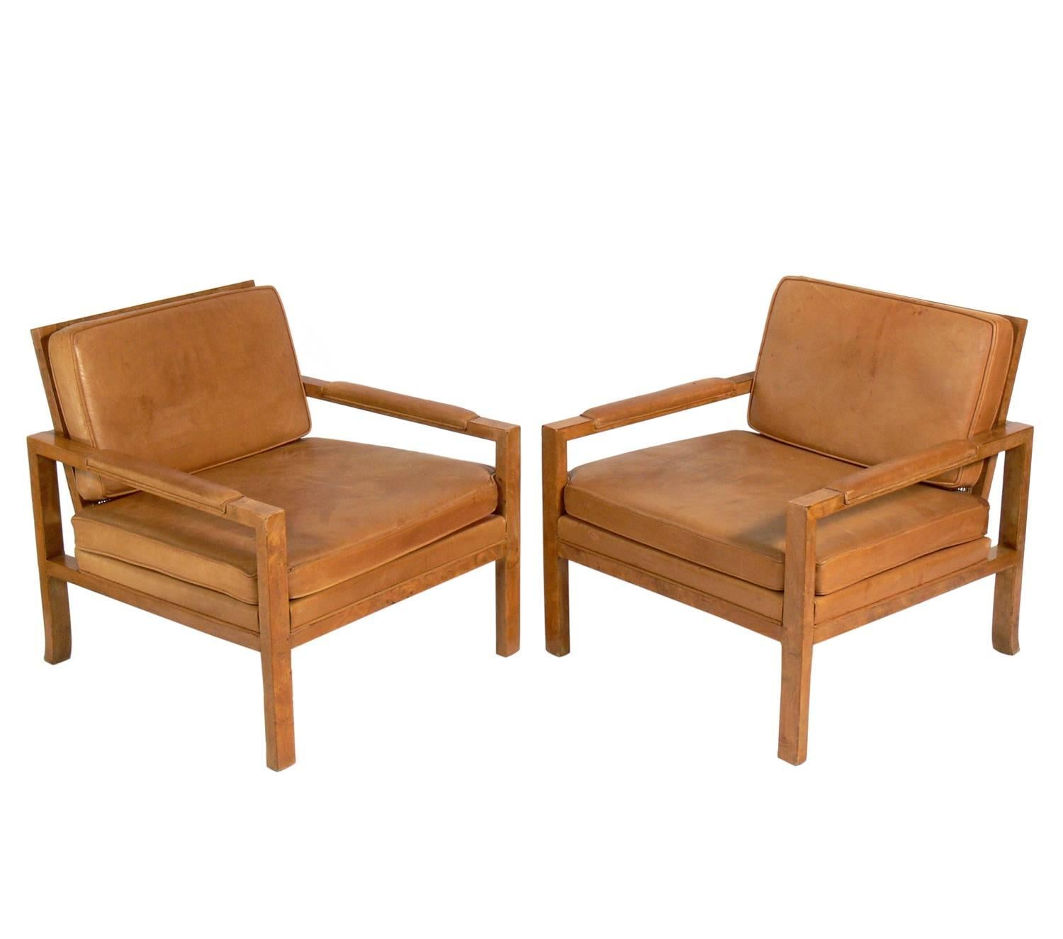 Pair of caned back burl wood lounge chairs in original saddle leather, American, circa 1960s. They retain their warm original patina to the burl wood frames and the saddle leather upholstery.