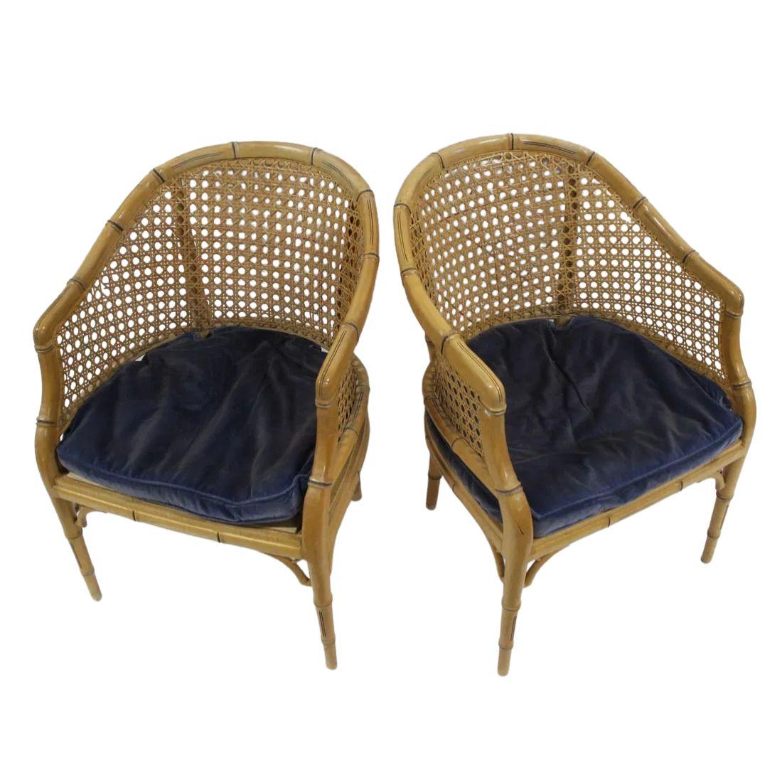 This pair of caned chairs features a distinctive curved tub shape, offering a comfortable and inviting seating experience. The frame is beautifully crafted with a bamboo form, showcasing a natural, organic aesthetic that complements both traditional
