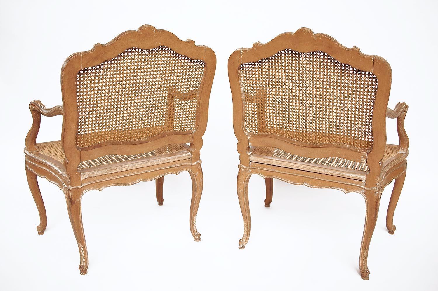 Pair of à la Reine Louis XV style canned armchairs in carved and cream lacquered wood standing on four cabriole legs with a decor of stylized cartouche and acanthus leaves, finishing by a scroll supported by a small shoe.
A la Reine canned back and