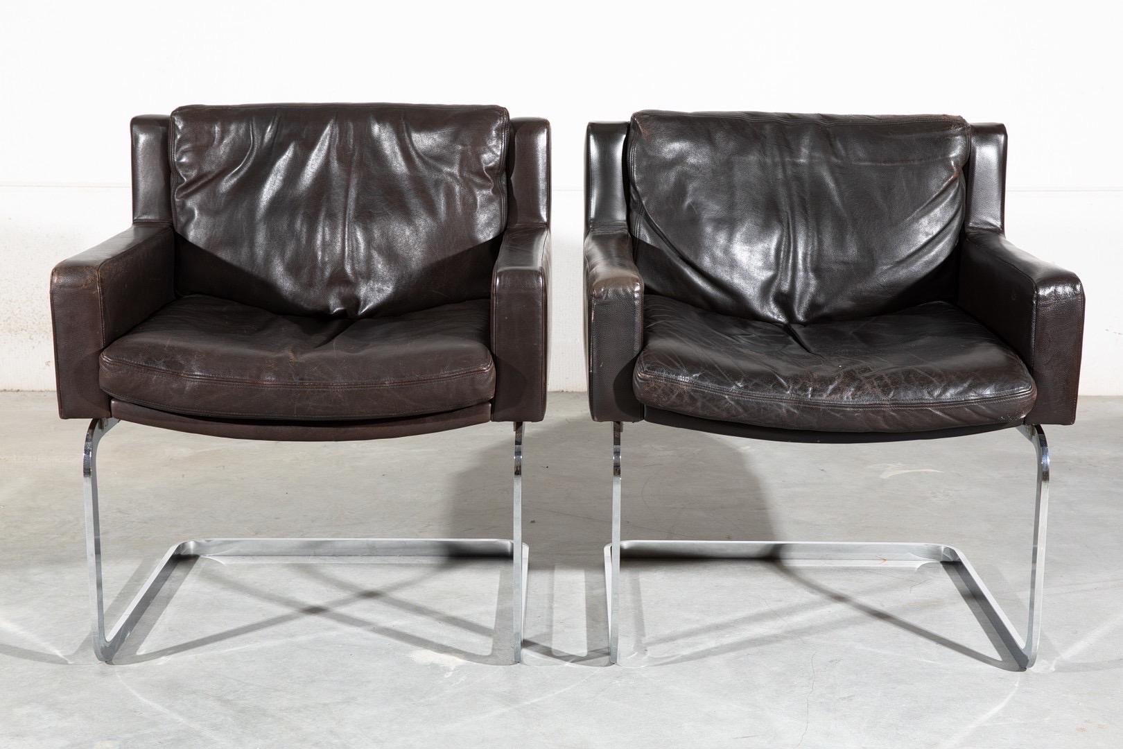 Robert Haussmann design “DS-201” for De Sede. Pair of mid century modern cantilever chairs. Upholstered in dark brown saddle leather with chrome cantilevered base. Made in Switzerland. Originally designed in 1957; these chairs date around