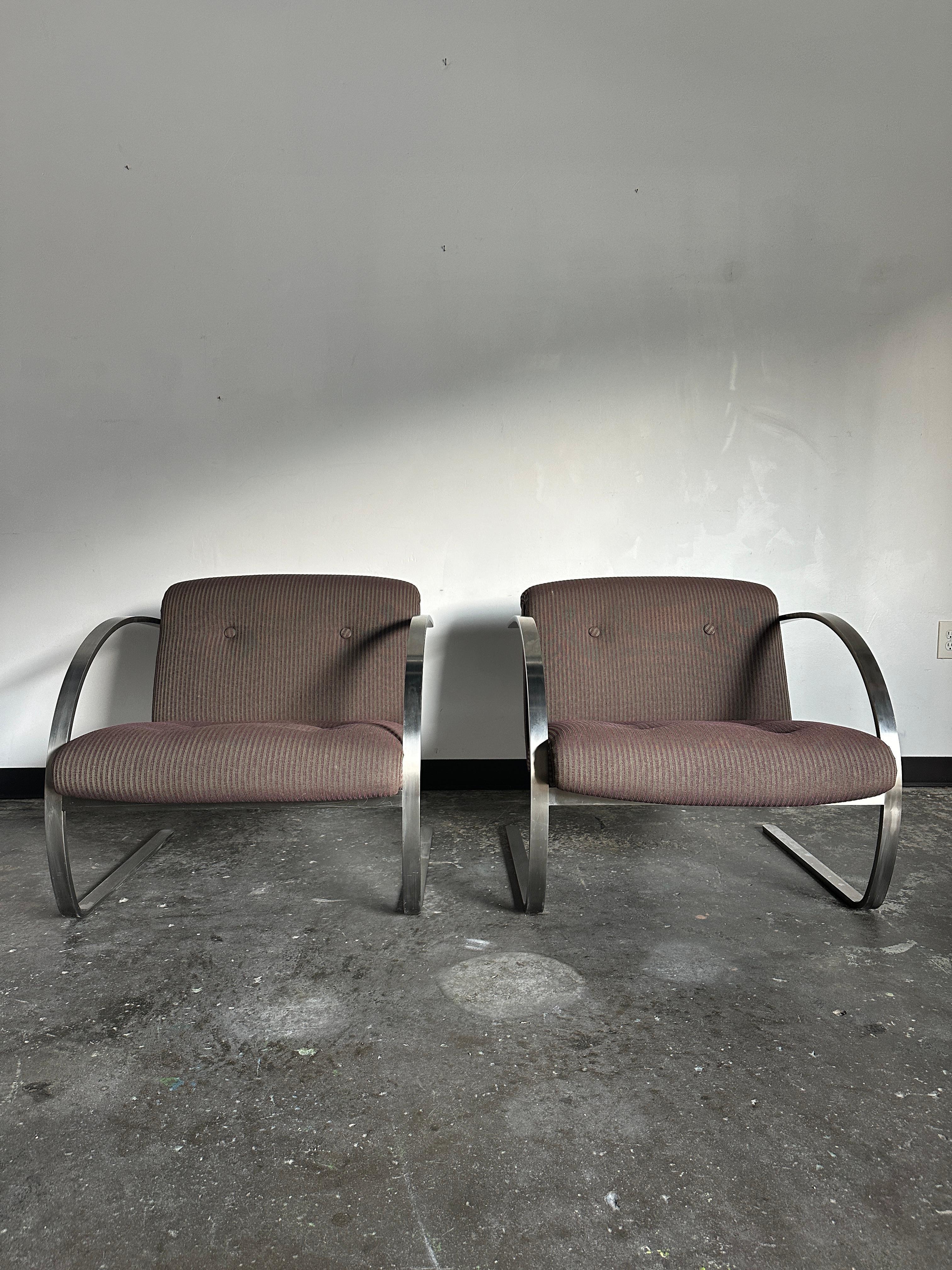 Labeled pair of  Arc cantilever lounge chairs by Charles Gibilterra for Brueton. Solid steel bar frame polished to a mirror finish with no signs of wear on the frame. Original striped tweed fabric has minimal, if any, age-consistent wear. Both the