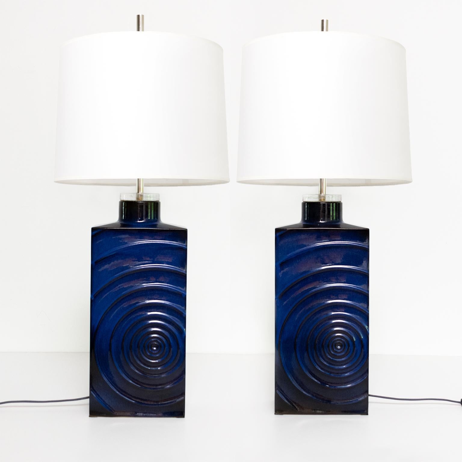 Pair of designer Carl Zalloni “Zykion” lamps made by Steuler, Germany circa 1960’s. The lamps are ceramic finished in a deep blue glaze and feature a raised asymmetrical circular pattern on the front and rear sides. The lamps have new chrome