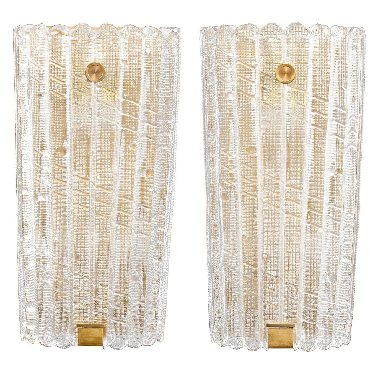 A large pair of fluted thick textured clear glass sconces on brass back plates with brass hardware by Carl Fagerlund for Orrefors.

Swedish, Circa 1940's

Three (3) Pairs Are In Stock.