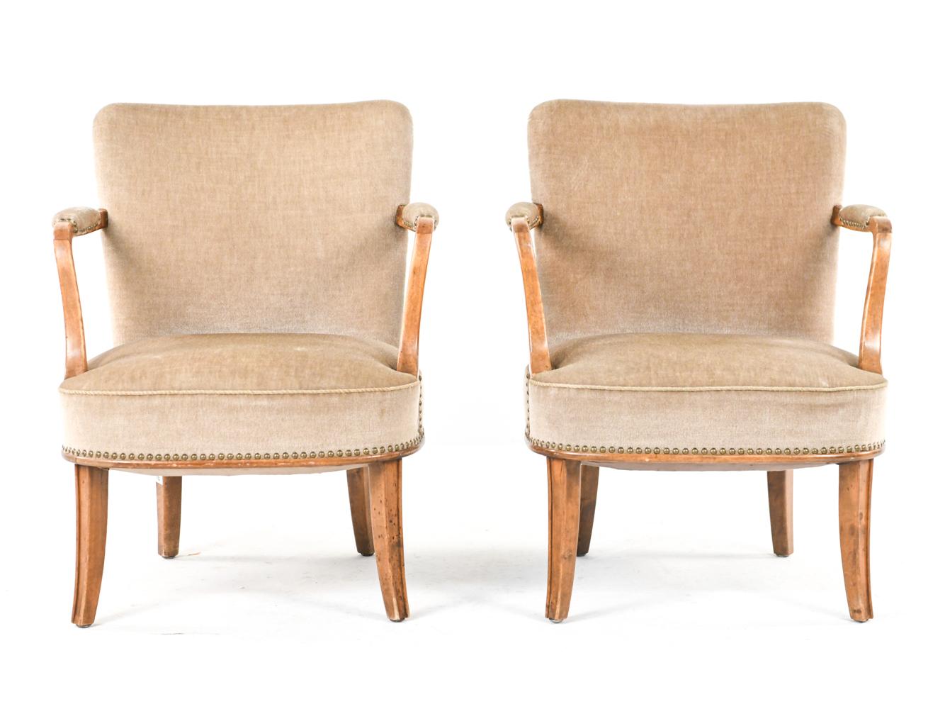A pair of Swedish mid-century easy chairs in the manner of Carl Malmsten. Upholstered in beige mohair, these chairs feature a nailhead trim detail.