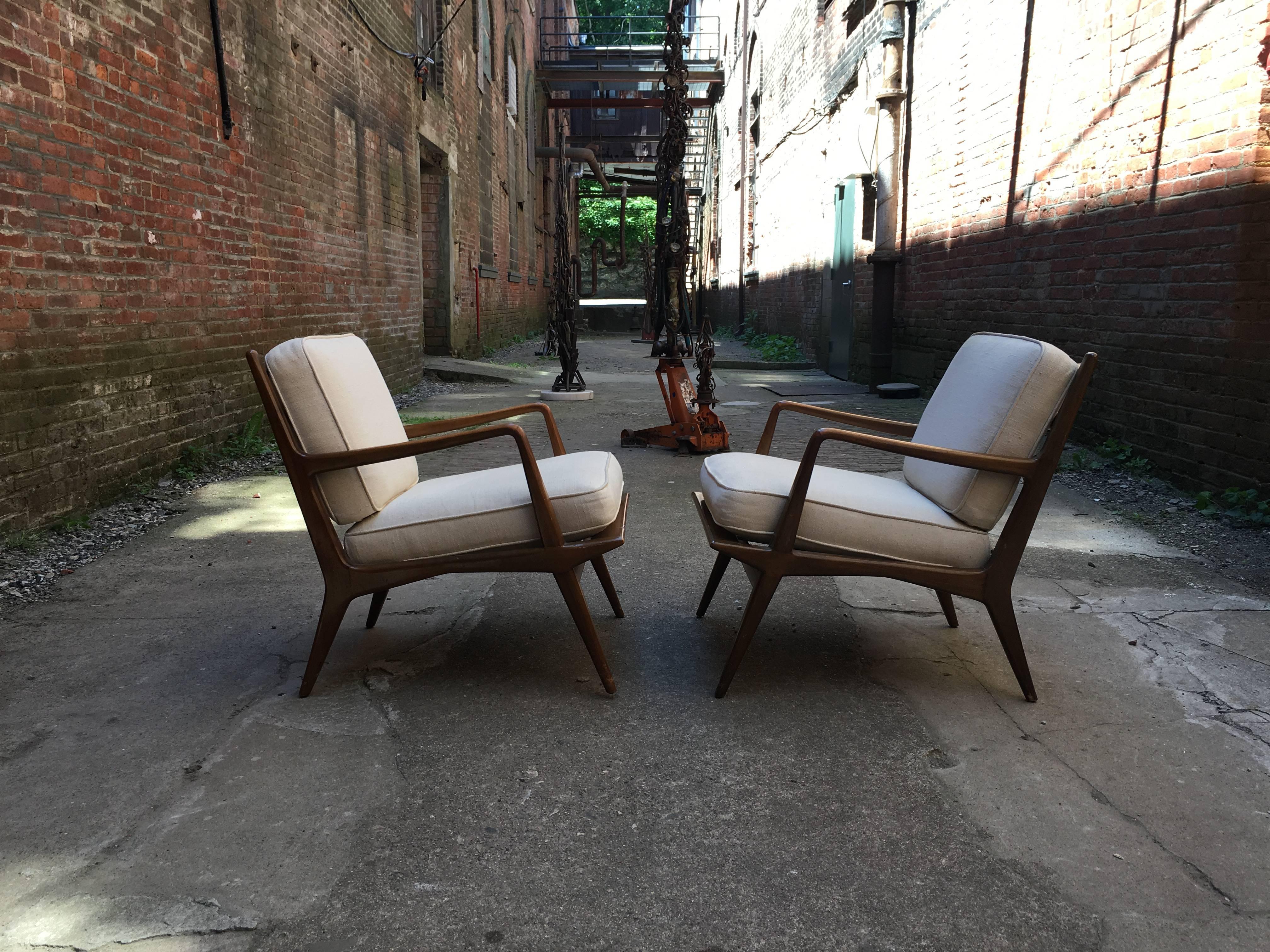 Beautiful walnut ladder back armchairs designed by Carlo di Carli for M. Singer & Sons. Elegant and sculptural pair of chairs retaining their original metal seat straps and splined rear leg detail. Upholstered white back and seat cushions. Original