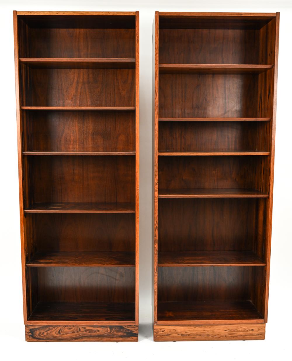 A beautiful pair of Danish mid-century bookcases designed by Carlo Jensen for Poul Hundevad, c. 1960's. This gorgeous minimalist design lets the beautiful rosewood veneer shine. With original Hundevad label to the back.