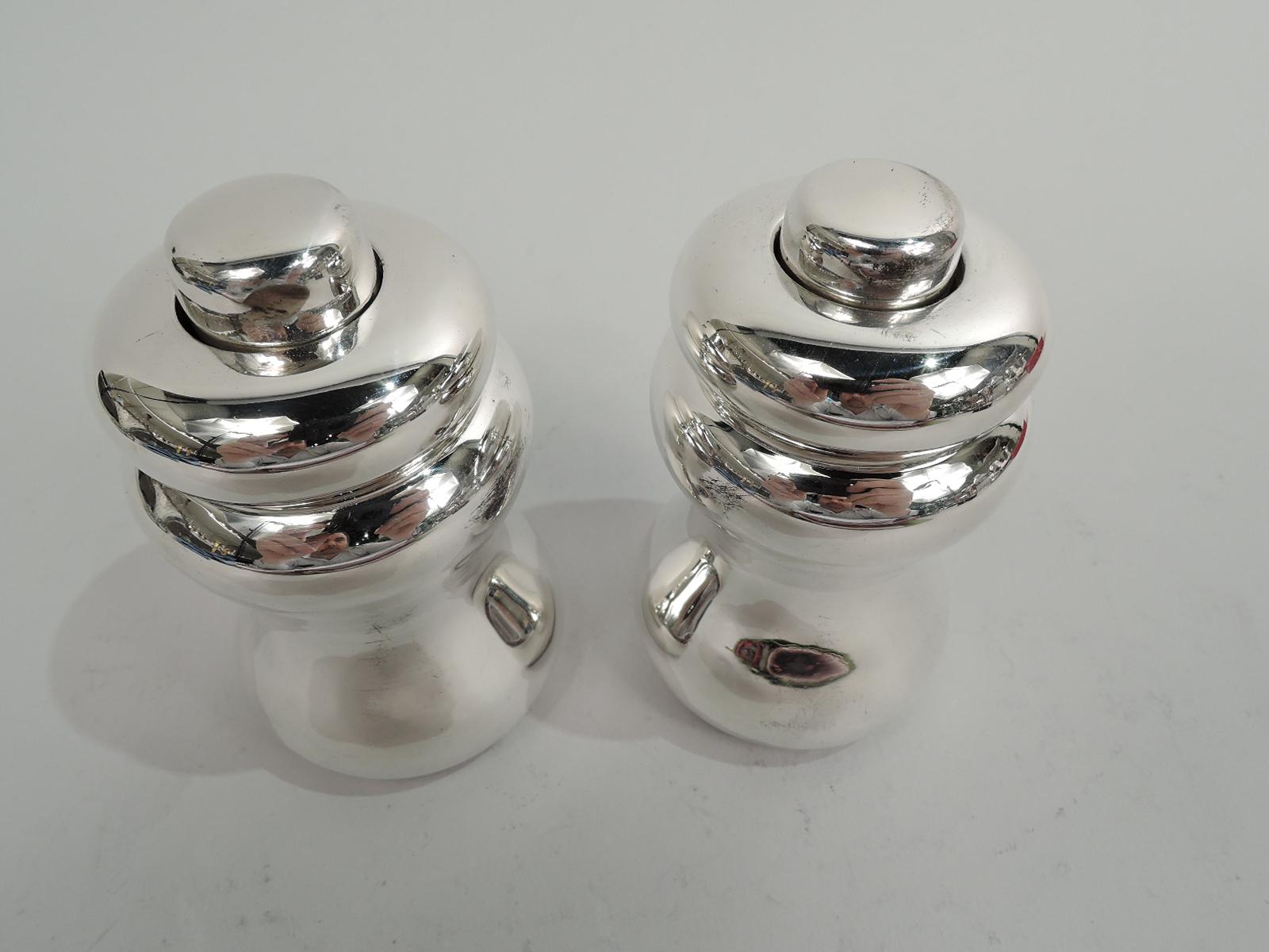 Pair of American Modern sterling silver pepper mills, ca 1930. Retailed by Cartier in New York. Waisted with rotating bun top and button finial. Fully marked including maker’s (Currier & Roby) and retailer’s stamps, and no. 5208A. Hardware marked