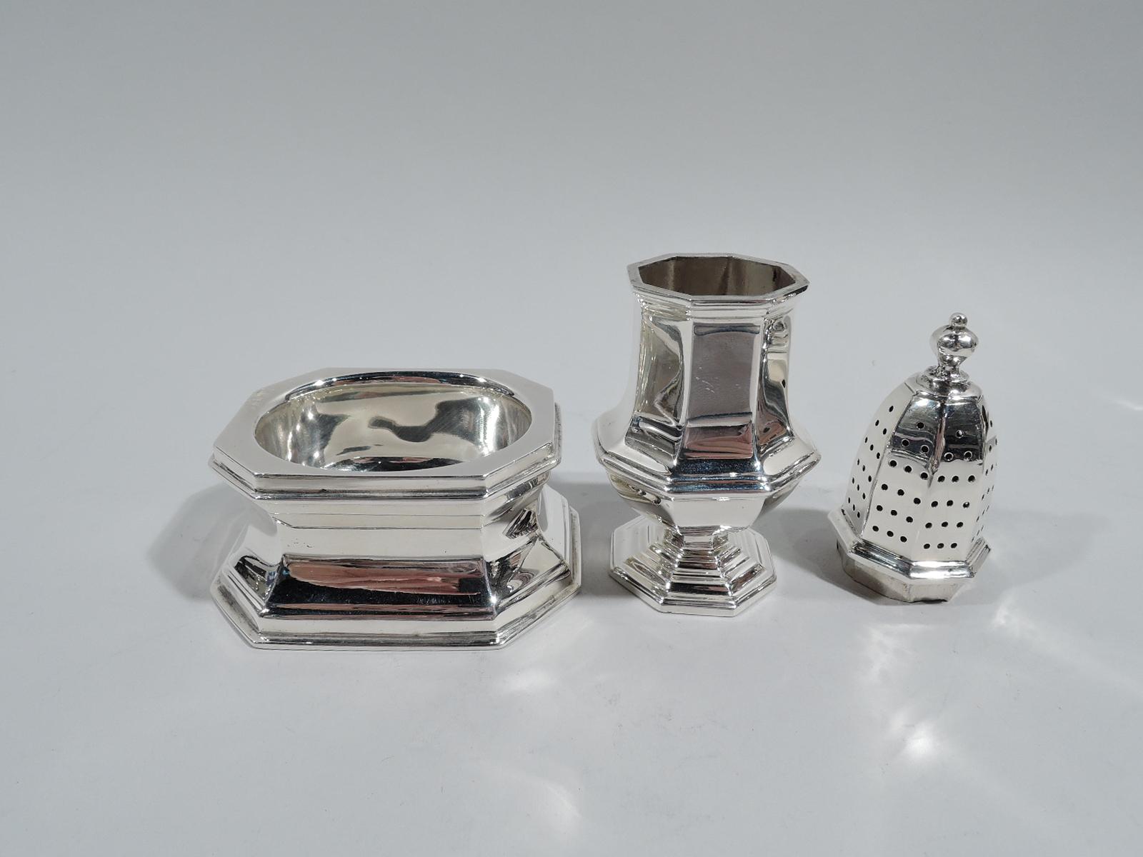 Pair of Modern Georgian sterling silver open salt and pepper shaker, ca 1930. Retailed by Cartier in New York. Salt: Oval bowl in rectilinear body with concave sides and chamfered corners. Pepper: Faceted baluster with stepped foot, pierced top, and