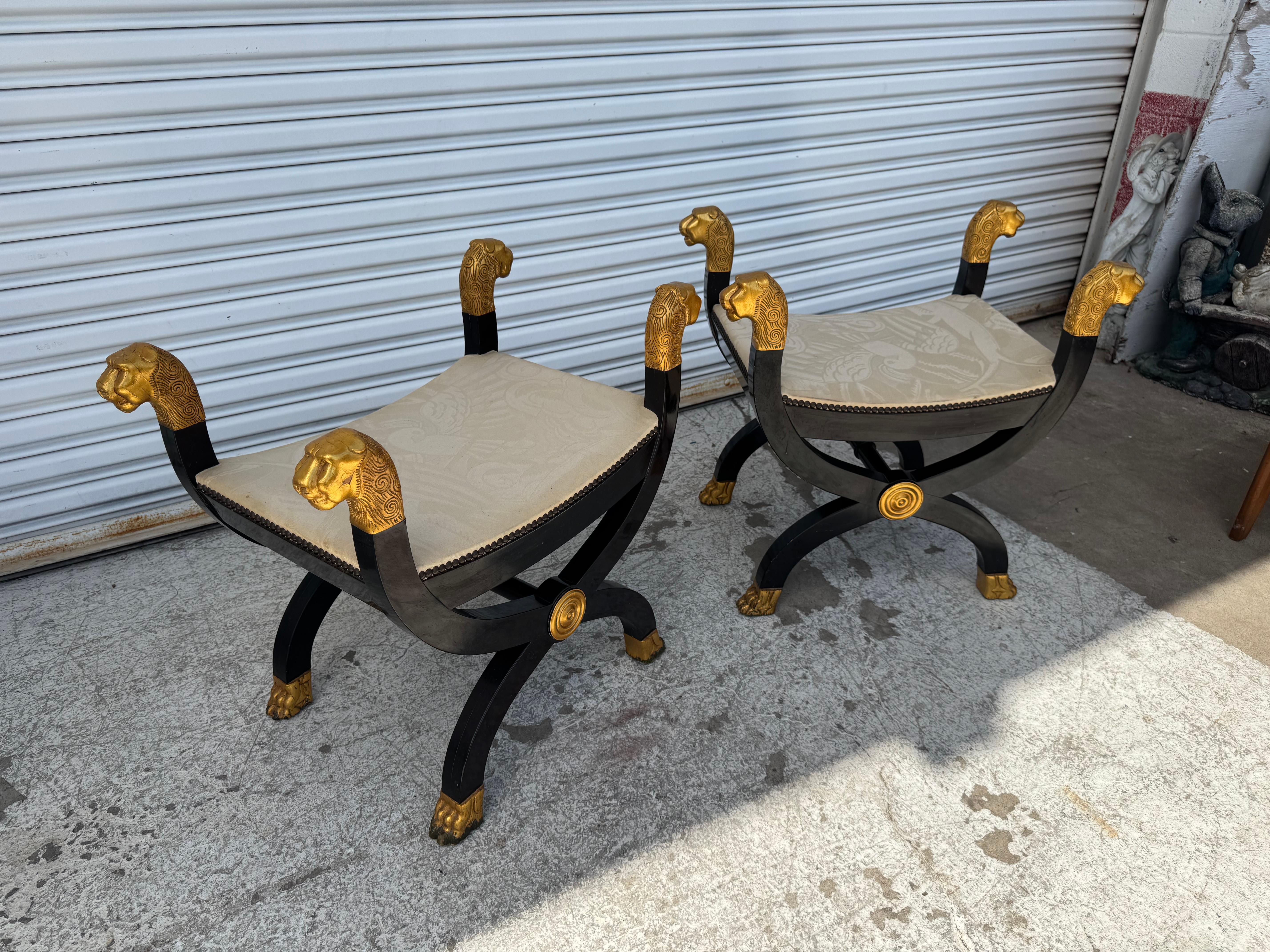 Coppia di sgabelli dorati con base a X di Curule.
Gli sgabelli sono laccati in nero e presentano teste di leone e piedi a zampa dorati.
Sono rivestite con un bel tessuto color guscio d'uovo.
Le gambe sono dotate di un'asta per garantire il