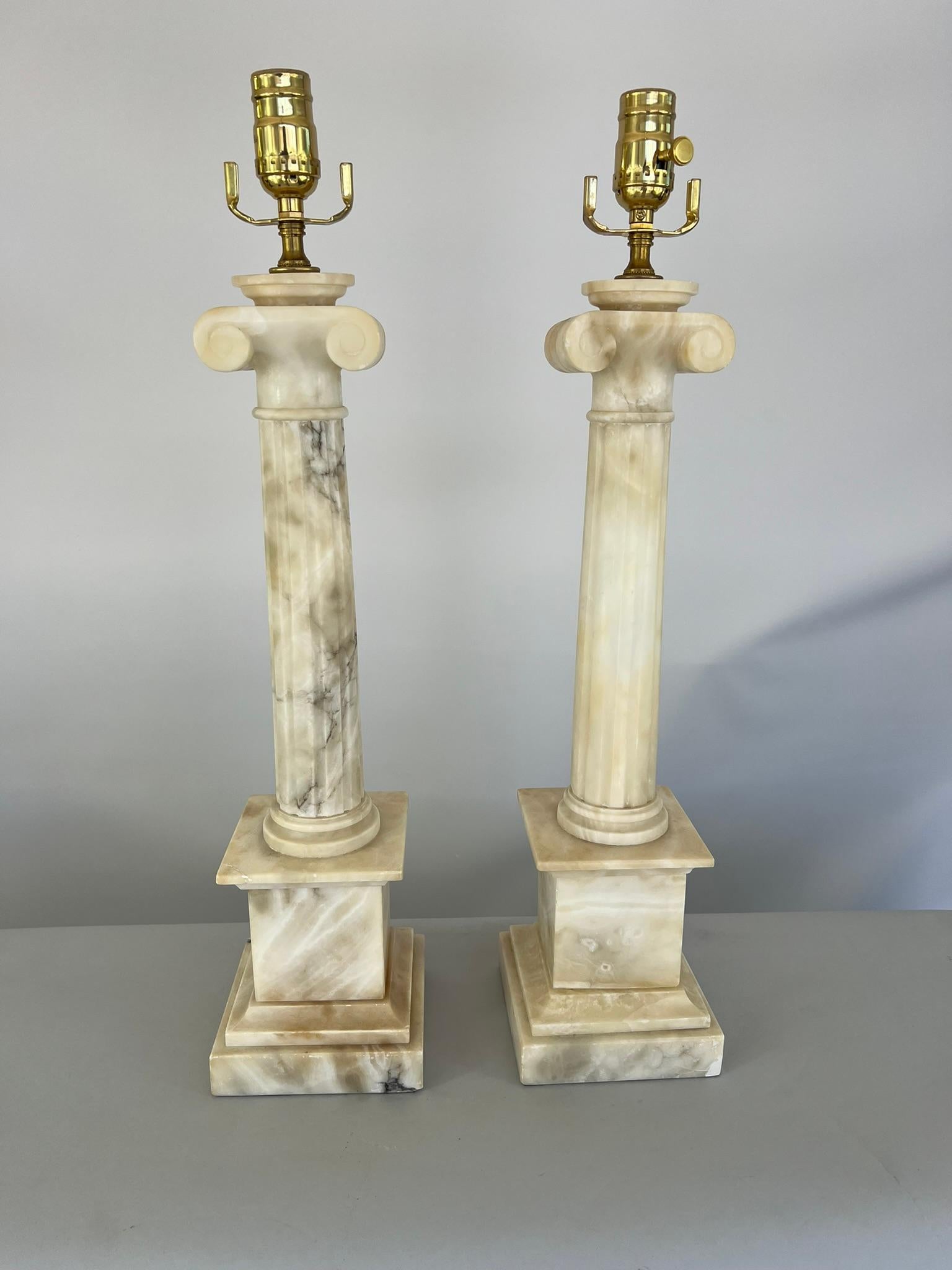 Pair of columnar-form table lamps, of carved alabaster, each a round, fluted, tapered column, with Ionic capital, on round foot, raised on square graduated plinth bases.

Stock ID: D3361.