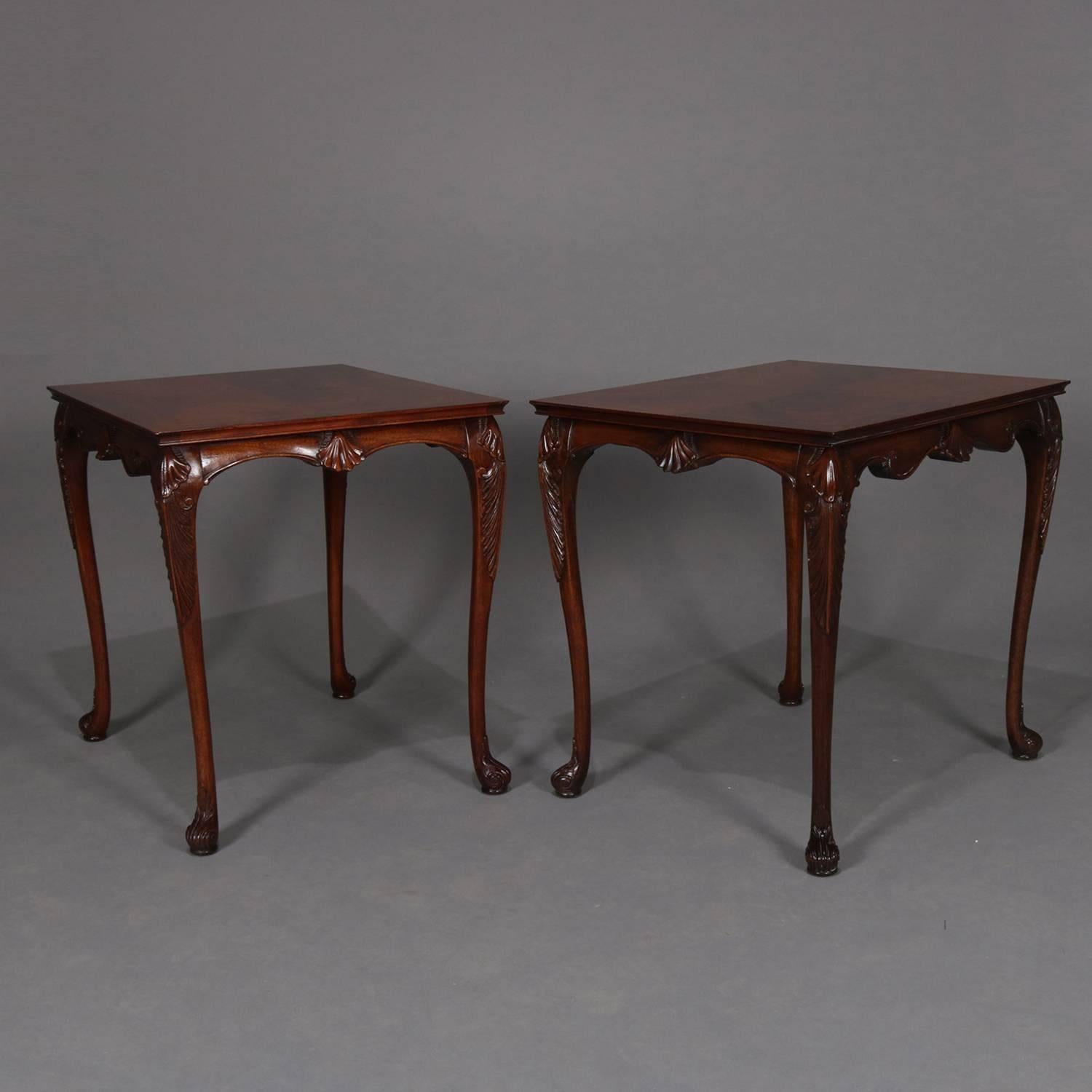 Pair of Baker School carved flame mahogany end table feature bookmatched tops with scalloped skirt having central shell and raised on cabriole legs with acanthus knees and scroll form feet, circa 1930.

Measures: 25.5