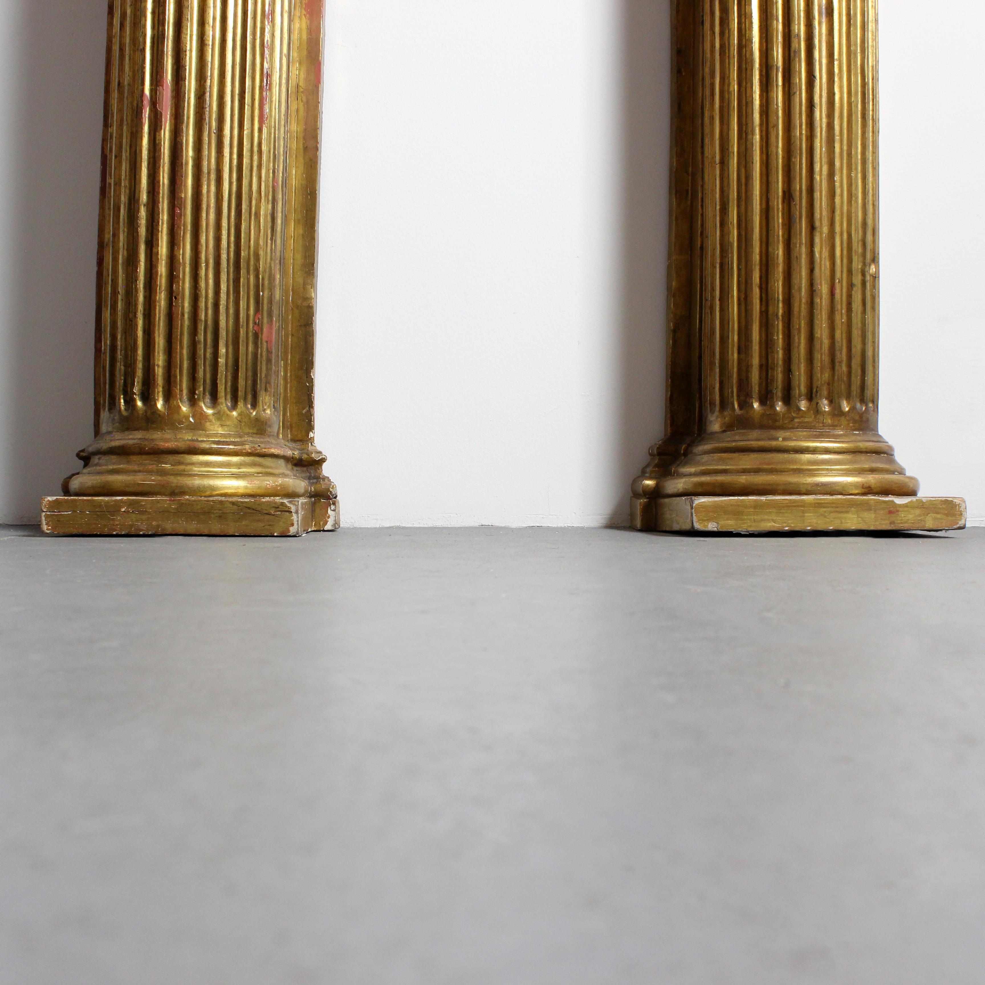 Pair of carved and gilded wall columns with fluted shafts and capitals topped Español en venta