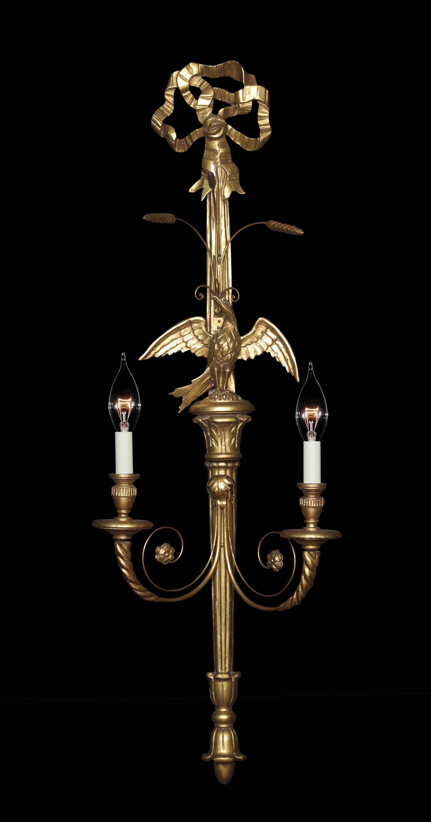 Pair of carved and gilded wall lights, each with central eagle flanked by a pair of scrolling branches, ribbon detail, and bow crest.

Dimensions
Height 45 Inches
Width 15 Inches
Depth 9.5 Inches